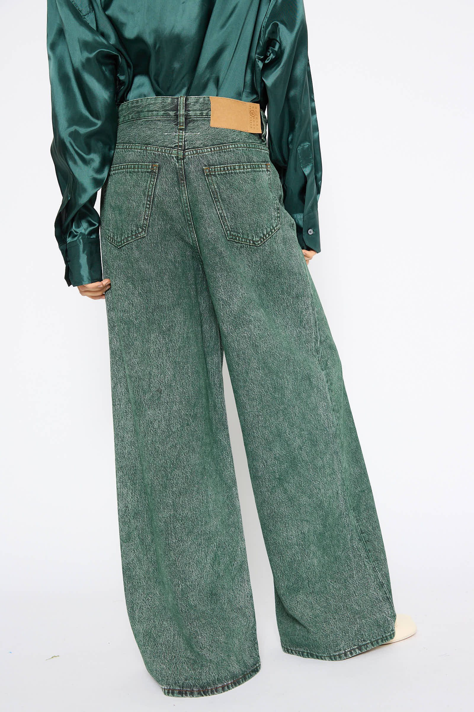 A person wearing a silk green shirt and MM6's 5 Pockets Denim Pant in Green stands facing away, showcasing the back side of the outfit.