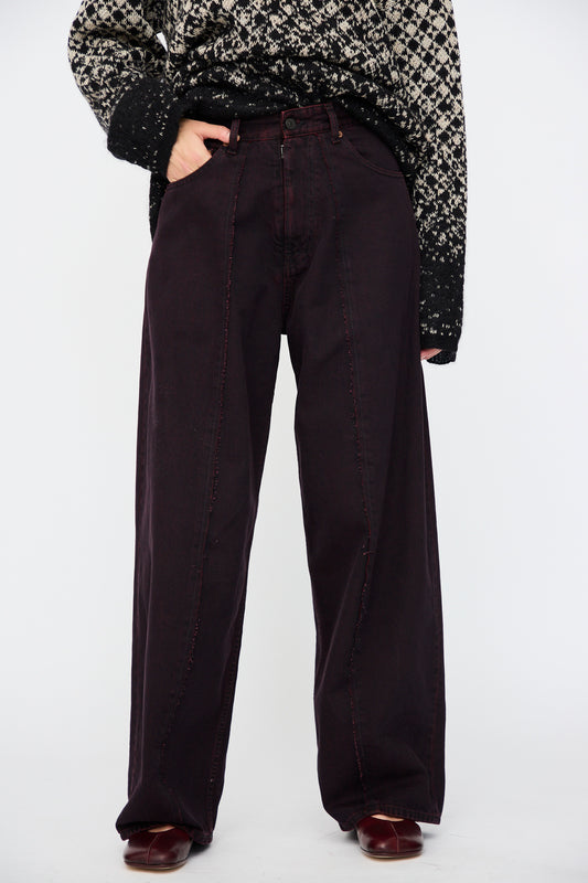 Model wearing a patterned black and white sweater, MM6 5 Pocket Pants in Burgundy with red stitching, and matching burgundy shoes, standing against a plain white background.