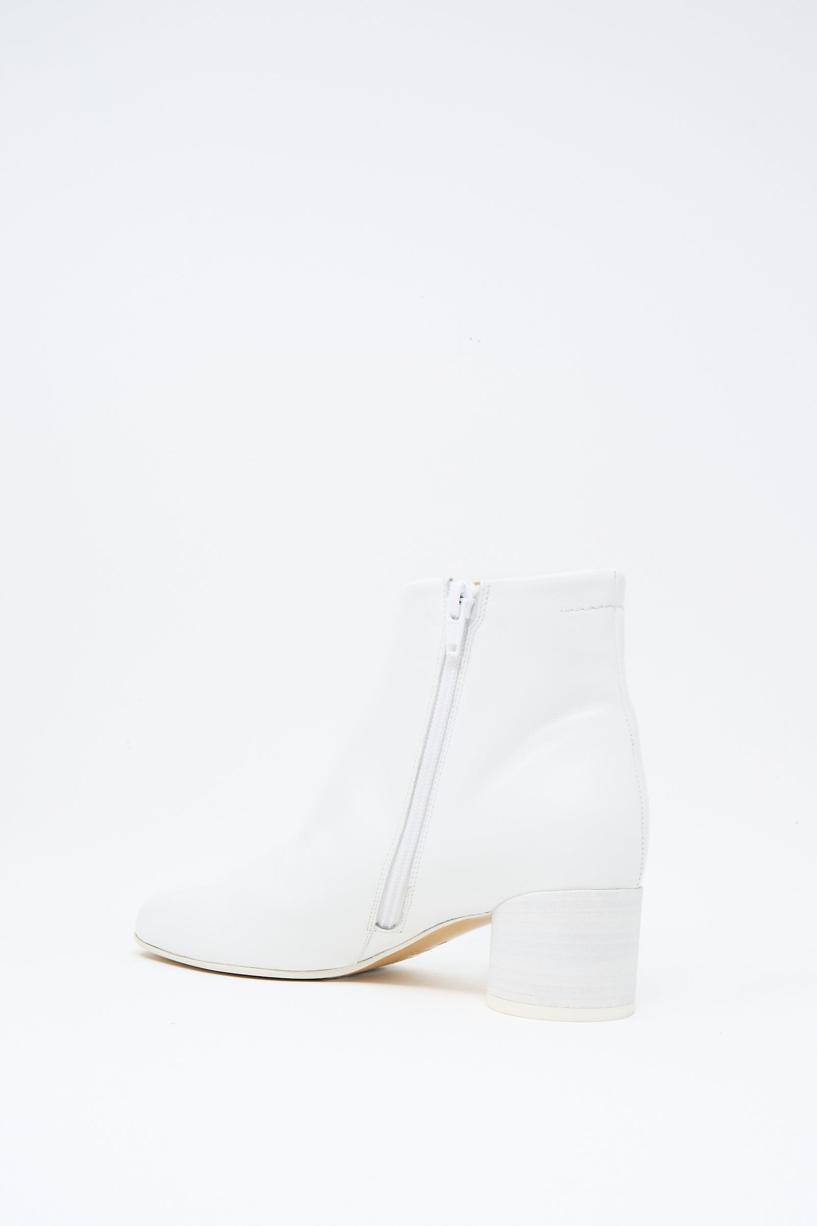 The MM6 Ankle Boot in White features a square toe, block heel, and side zipper. Crafted from buffed calfskin leather, the ankle-high boot is shown against a plain white background.