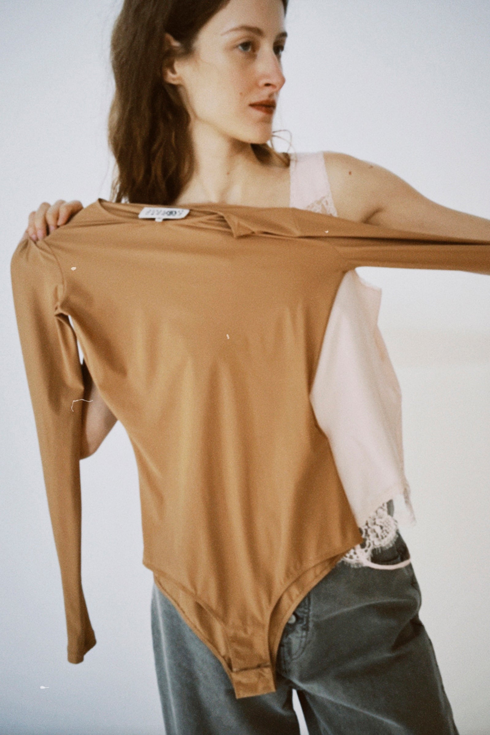 A woman holding up the MM6 Bodysuit in Miami.