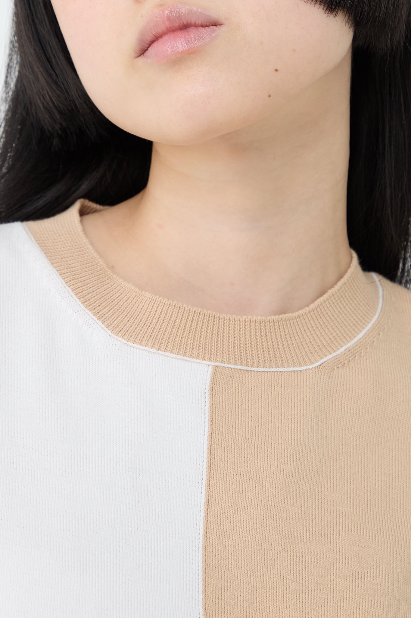 A woman wearing a MM6 relaxed fit, bi-color cotton sweater in Beige Off White.
