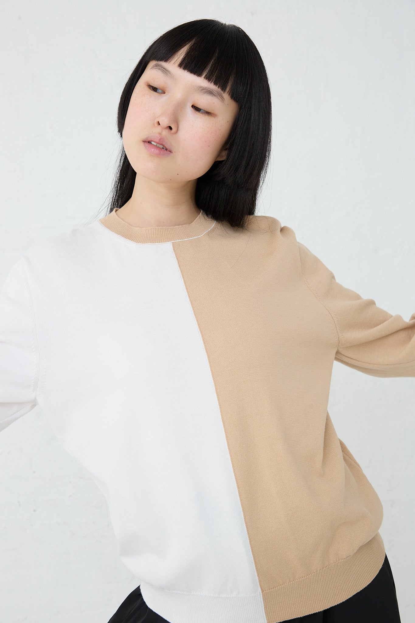 A relaxed-fit model wearing a MM6 bi-color cotton Crewneck in Beige Off White sweater.