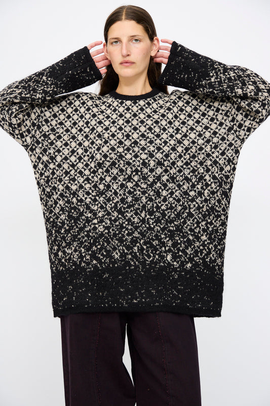 A person wears the MM6 Crewneck in Black and Beige with dark pants, standing against a plain white background.
