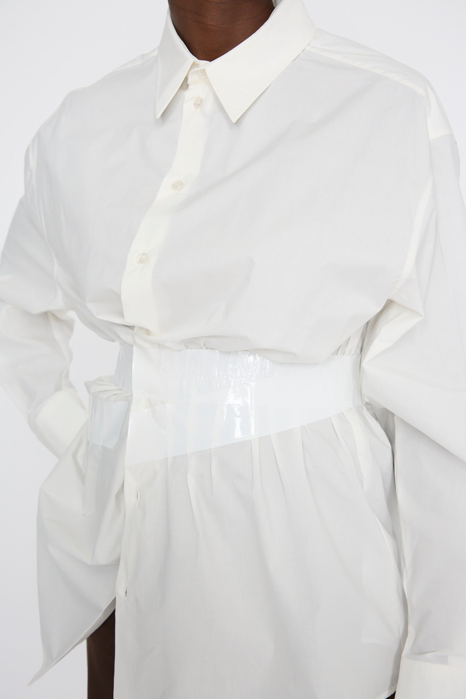 A person wearing an MM6 Long Sleeve Shirt in Off White, paired with a glossy white belt.