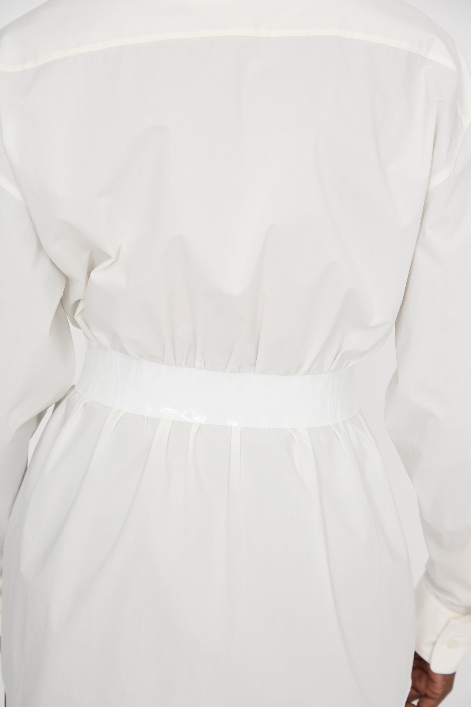 A person is seen from the back wearing MM6’s Long Sleeve Shirt in Off White, featuring a glossy white belt and crafted from relaxed-fit cotton poplin.