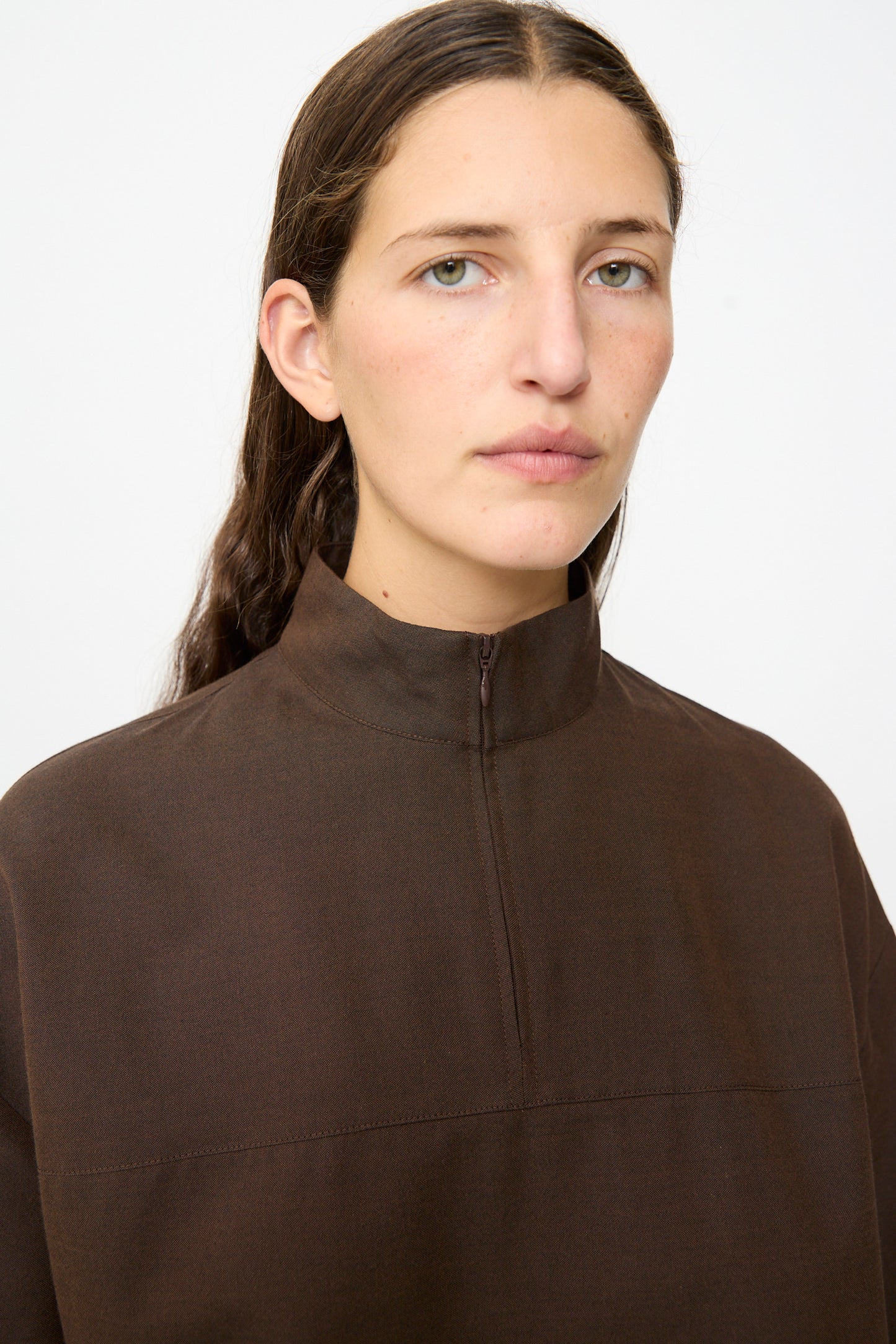 A person with long brown hair is wearing the MM6 Maxi Dress in Brown, crafted from a luxurious wool-cotton blend, standing against a plain white background.