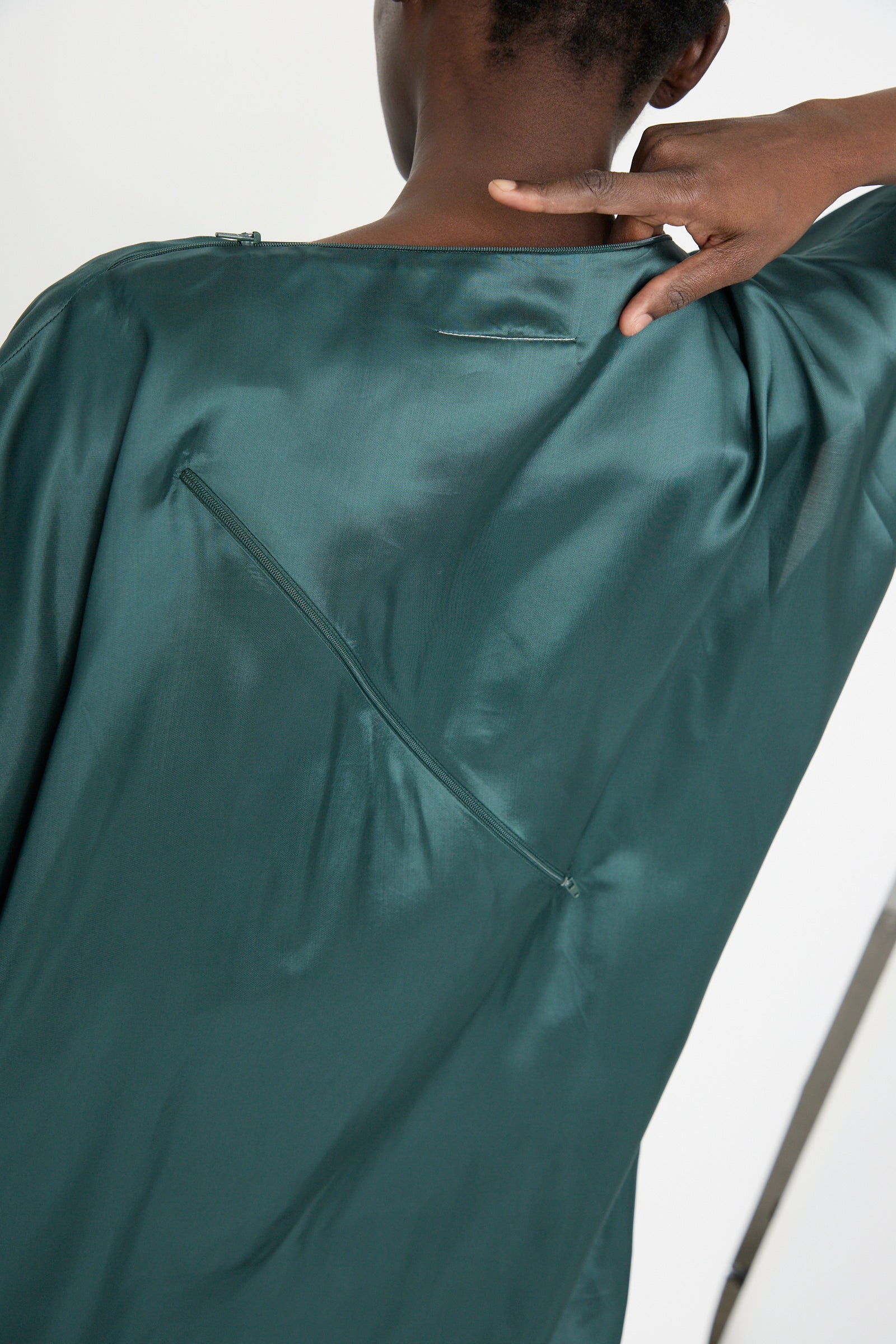 A person is shown from behind wearing the MM6 Maxi Dress in Green, highlighted by a unique diagonal seam and pocket detail.