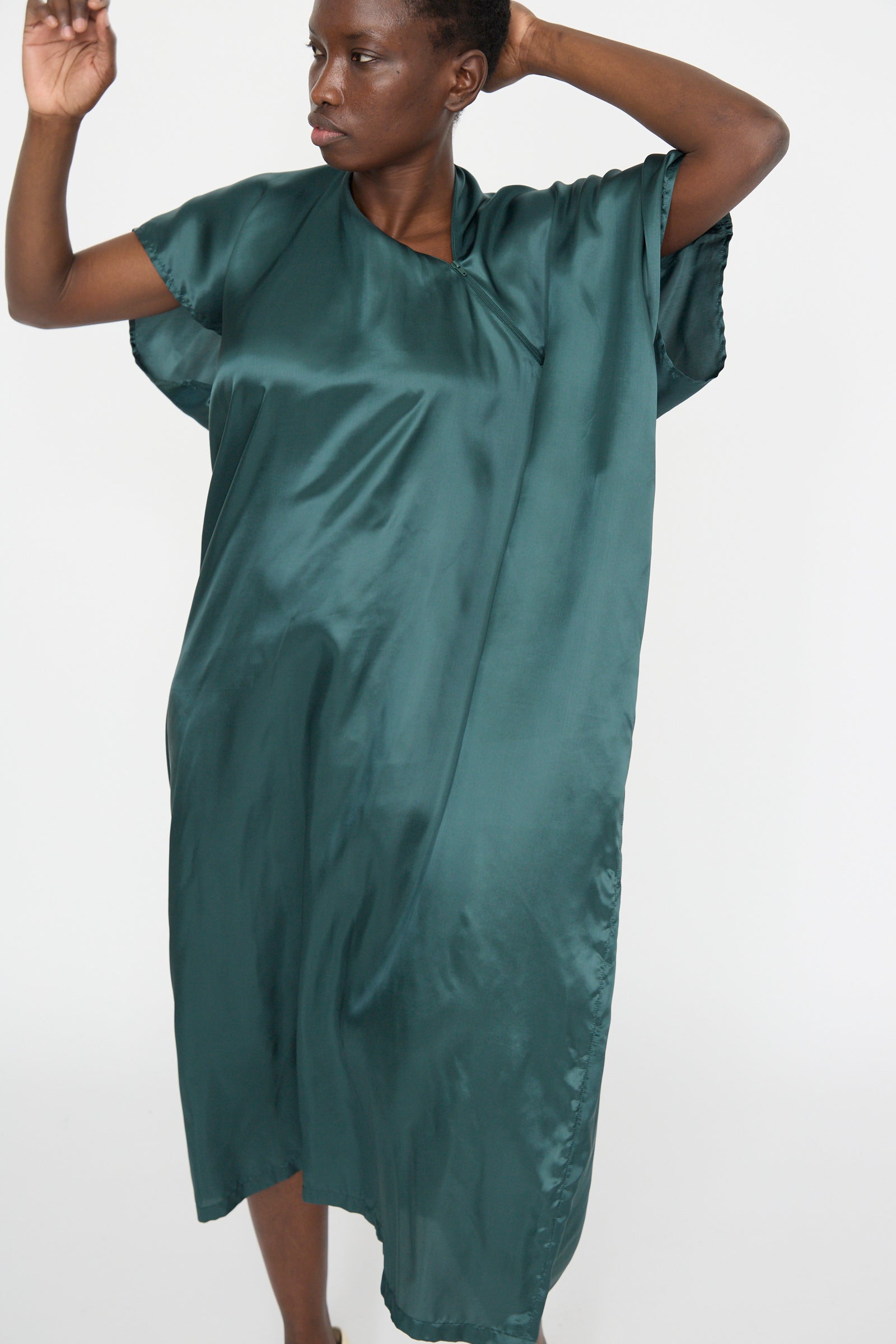 A model poses against a plain white background wearing the Maxi Dress in Green by MM6, showcasing its elegant oversized fit.