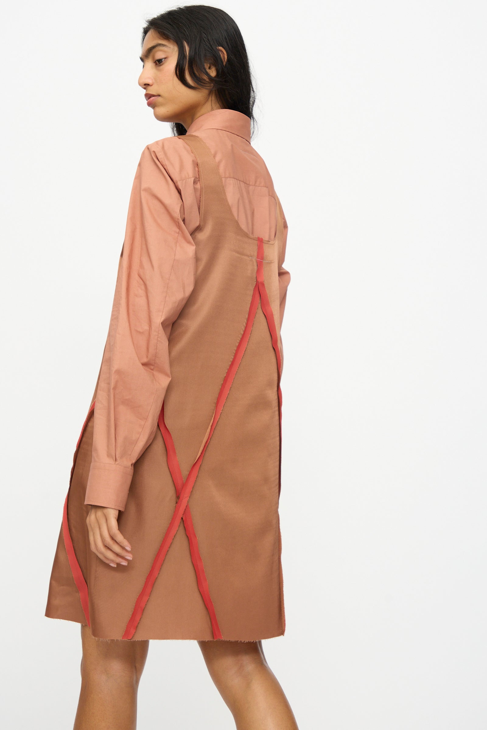 A woman wears the MM6 Midi Dress in Light Brown, featuring long sleeves and red diagonal and vertical lines on the back, made from an acetate blend, standing against a plain white background.