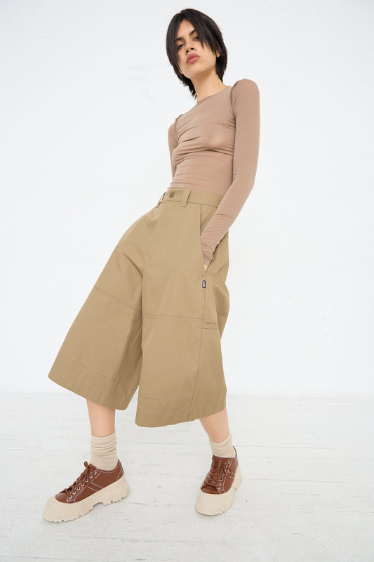 Woman posing in MM6's beige oversized shorts with pockets and a fitted long-sleeve top, paired with brown chunky boots.