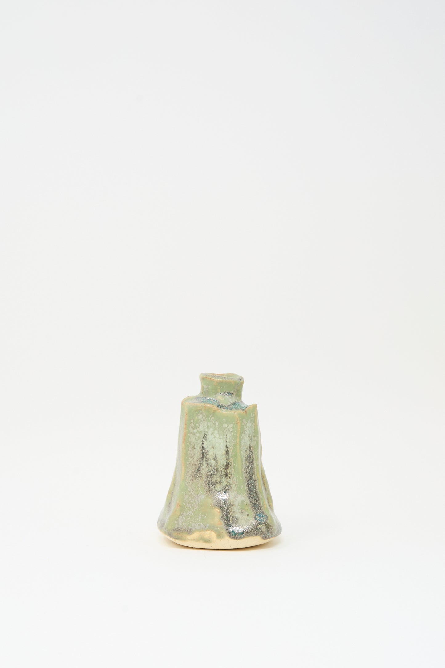 The MONDAYS Carved Bud Vase in Lichen Green features an irregular handmade shape and mottled green and beige glaze, displayed against a plain white background.