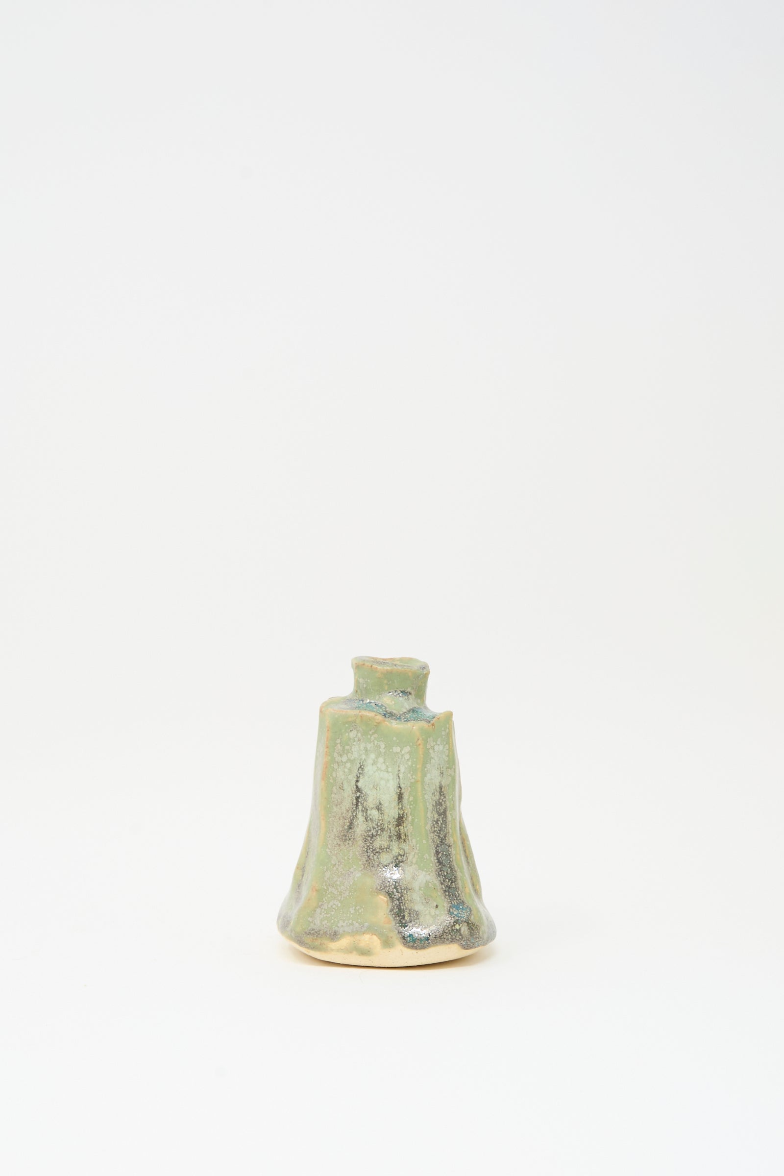 The MONDAYS Carved Bud Vase in Lichen Green features an irregular handmade shape and mottled green and beige glaze, displayed against a plain white background.