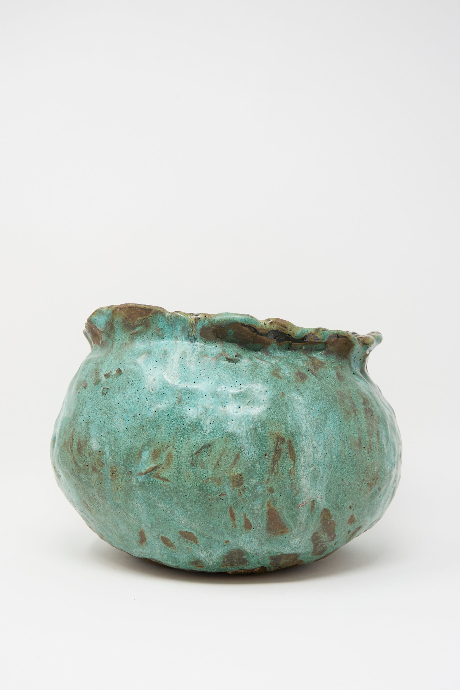 The Coiled Urn in Green by MONDAYS is a round, hand-built stoneware vessel featuring a wide mouth, uneven rim, and a mottled turquoise and green glaze with brown accents.