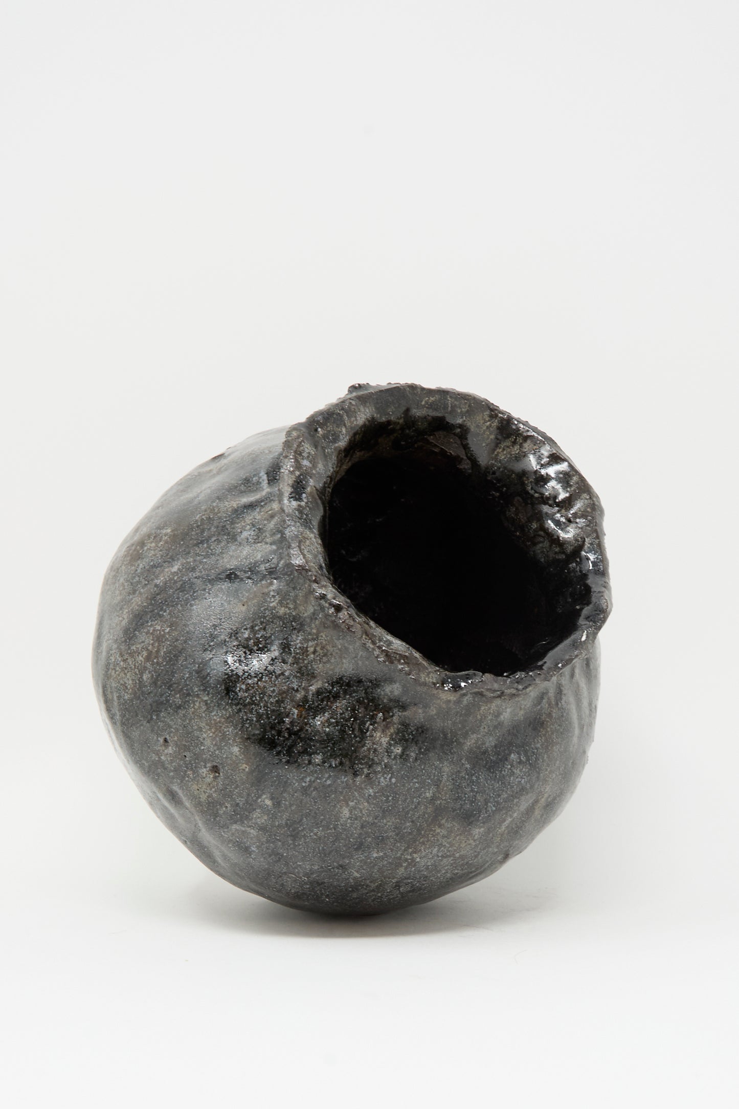 The Coiled Vase in Black by MONDAYS is an irregularly shaped, hand-coiled piece with a rough, uneven surface and wide jagged opening, crafted in Brooklyn and showcased on a plain white background.