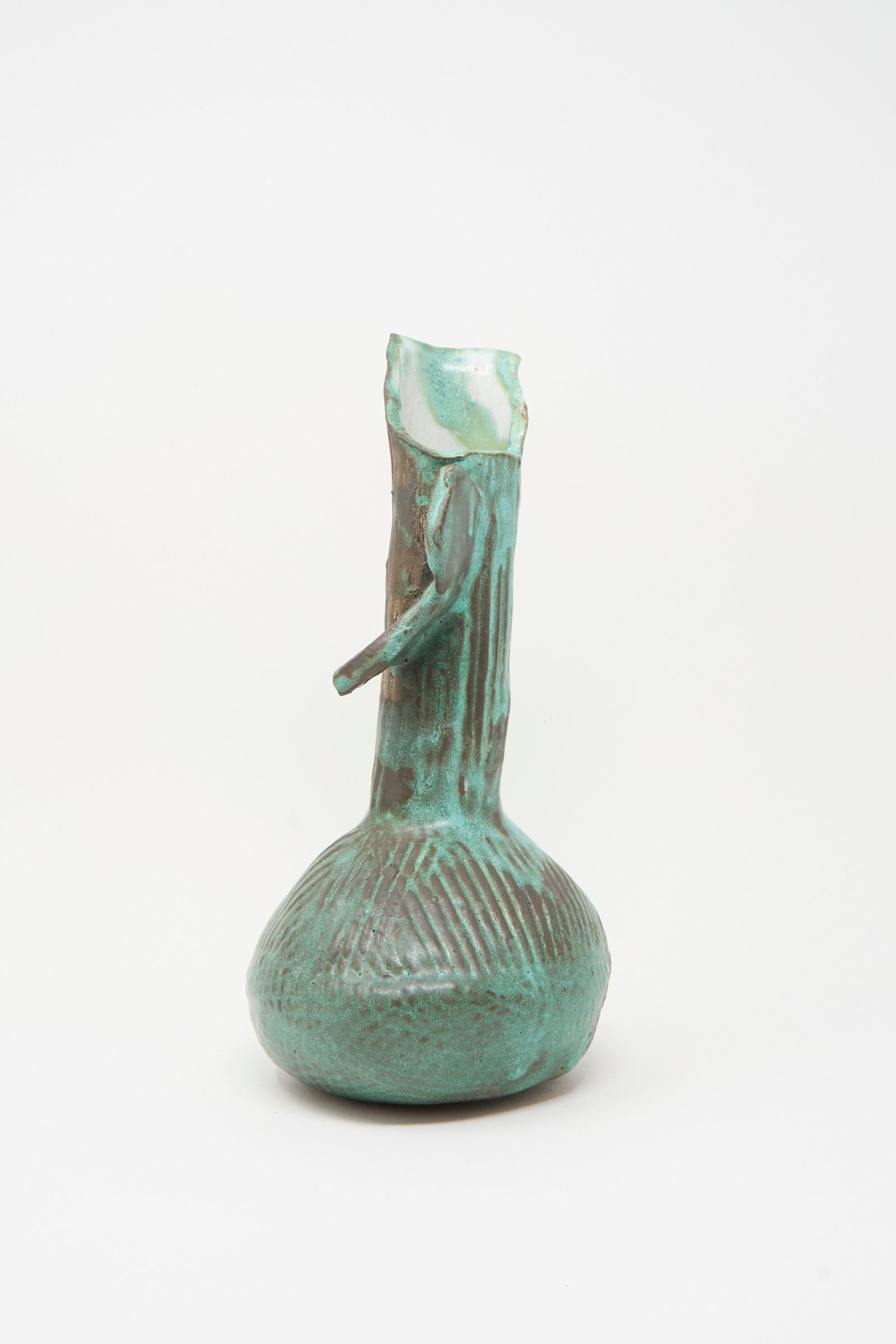 The Corrugated Pitcher in Green II by MONDAYS is a handmade sculptural piece from Brooklyn pottery, featuring a bulbous base, narrow neck, broken top, textured vertical lines, and a glossy green glaze.