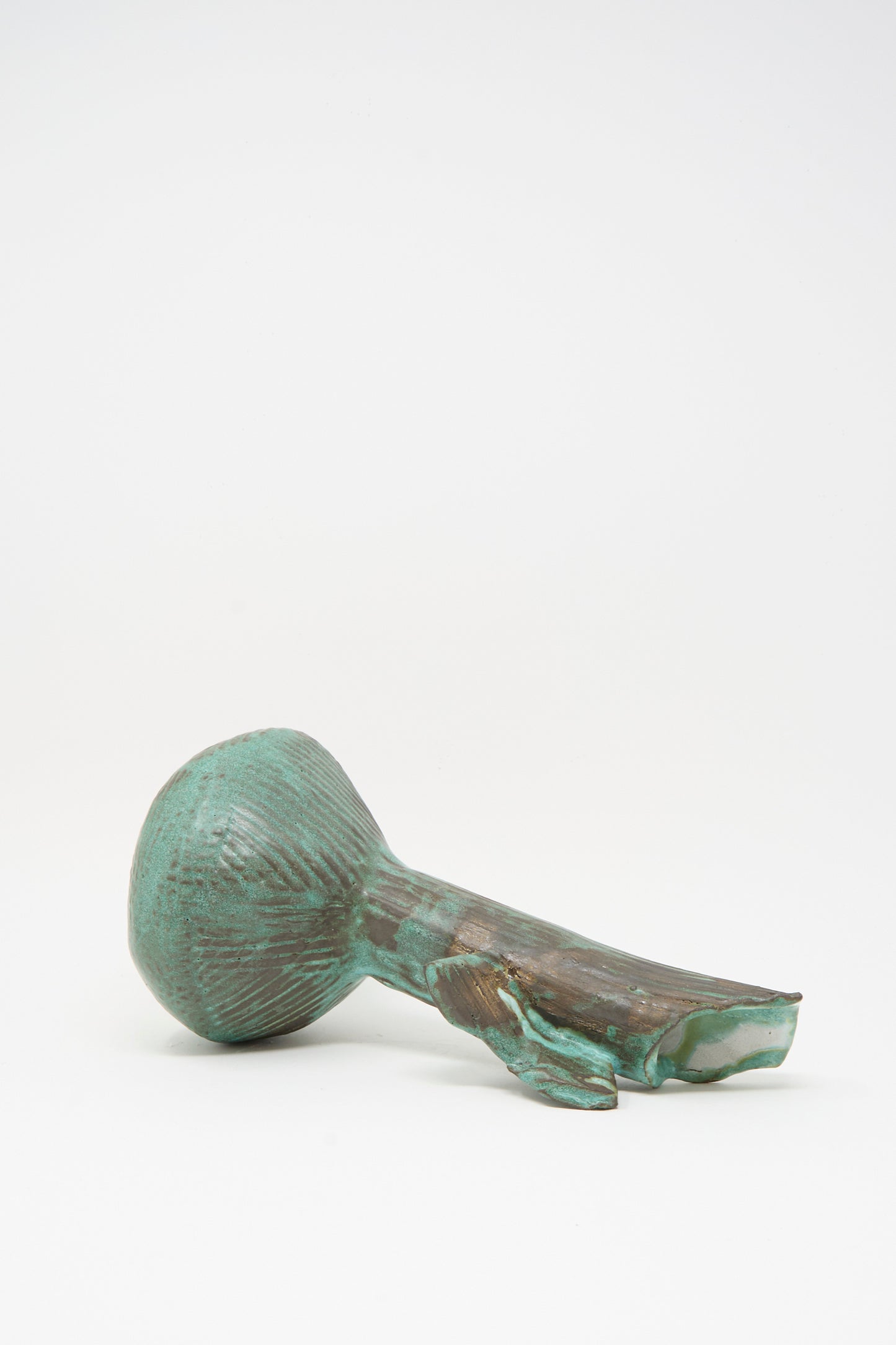The MONDAYS Corrugated Pitcher in Green II is a handmade sculptural piece featuring a round, ridged bulb and a jagged, fractured handle, displayed against a plain white background.