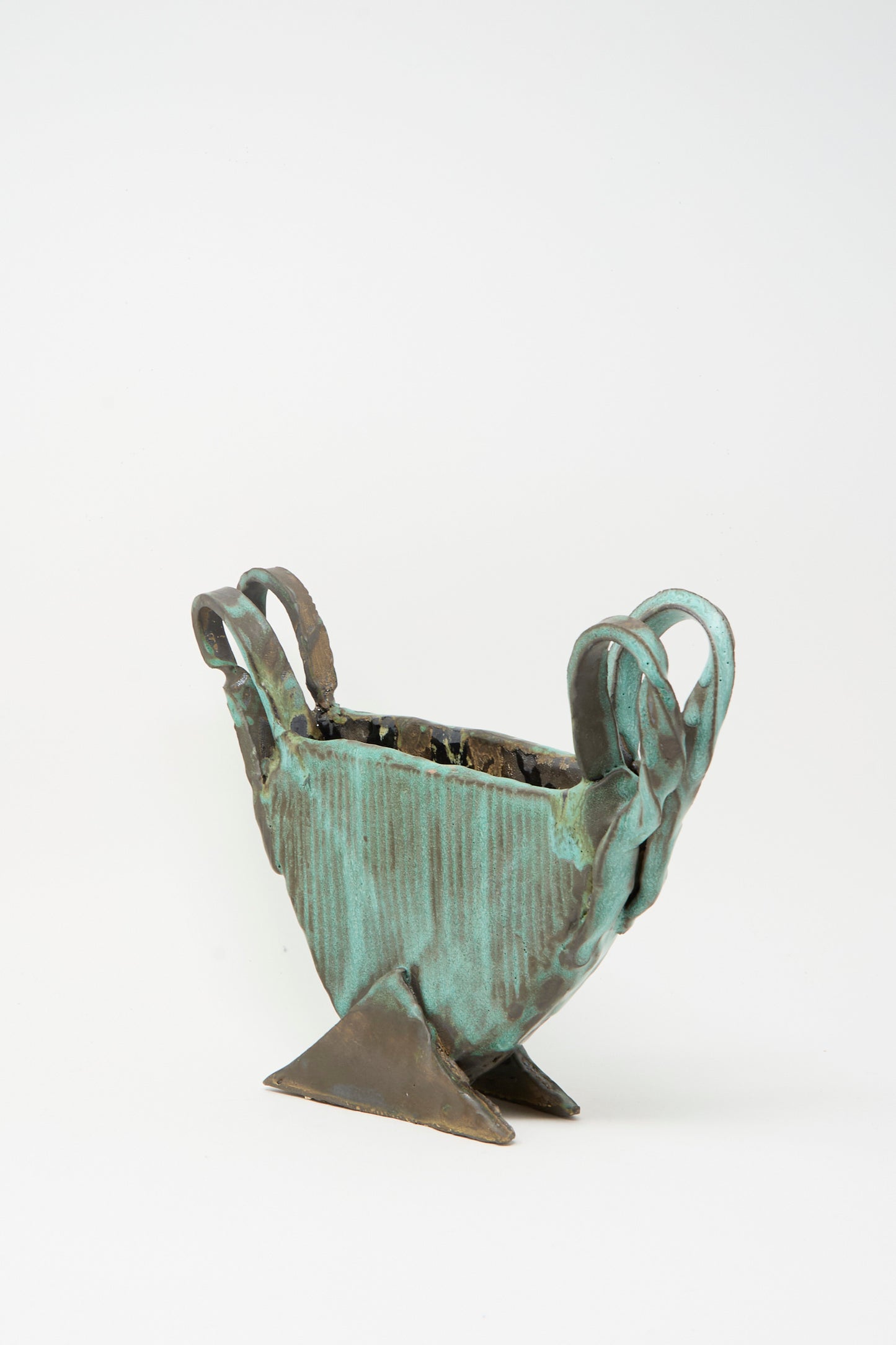 The Corrugated Vessel with Handles in Green by MONDAYS features a textured, geometric design with three handles and an angular base. This handmade ceramic piece is crafted in Upstate NY and is presented against a plain white background.