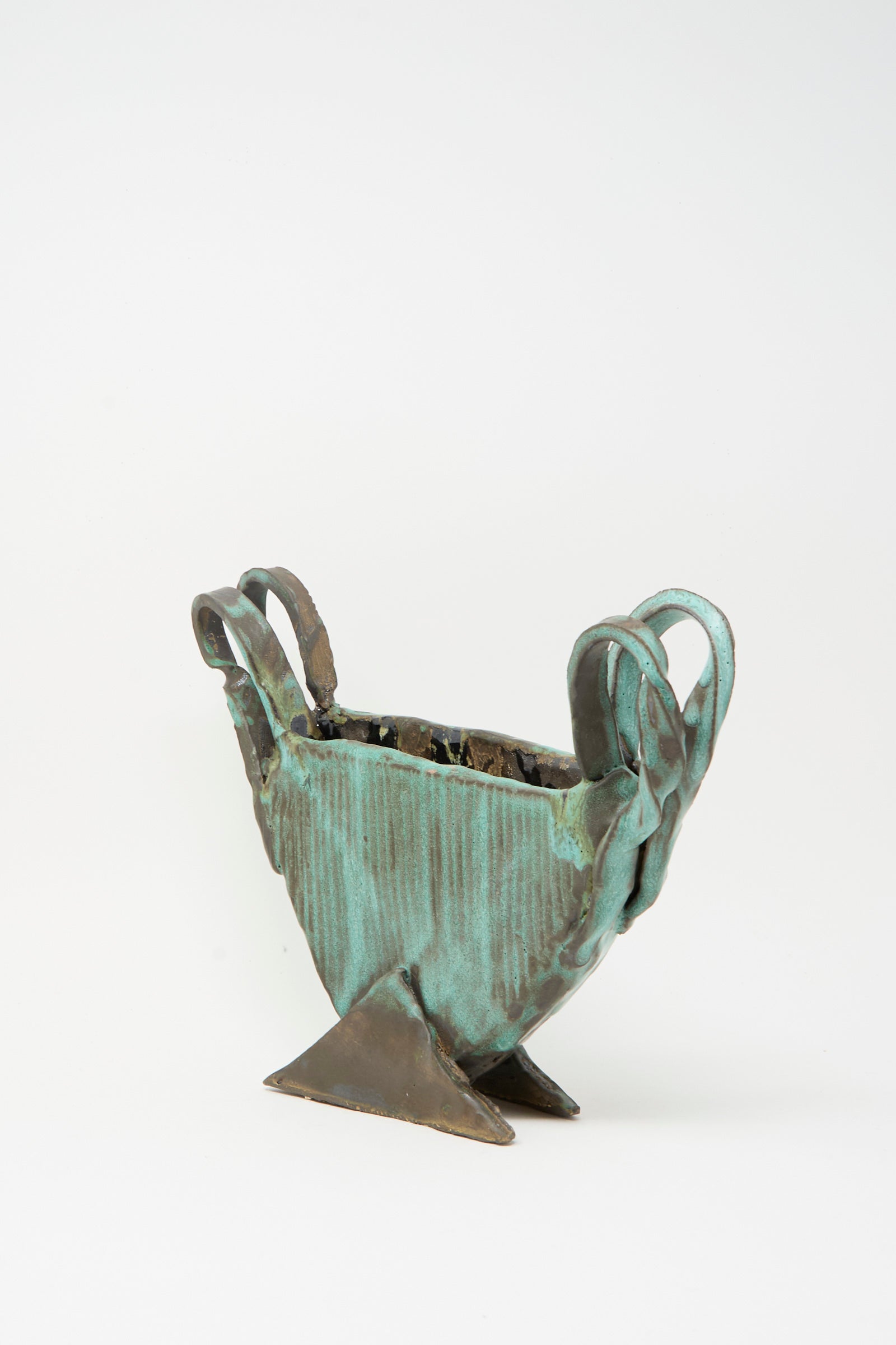 The Corrugated Vessel with Handles in Green by MONDAYS features a textured, geometric design with three handles and an angular base. This handmade ceramic piece is crafted in Upstate NY and is presented against a plain white background.