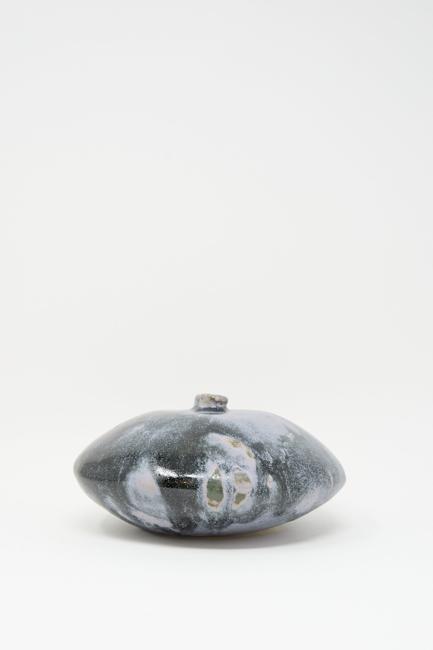 The Doyle Vase in Storm by MONDAYS is a handmade, round, flat dark gray vase with a small neck and white and light gray patterns, shown against a plain white background.