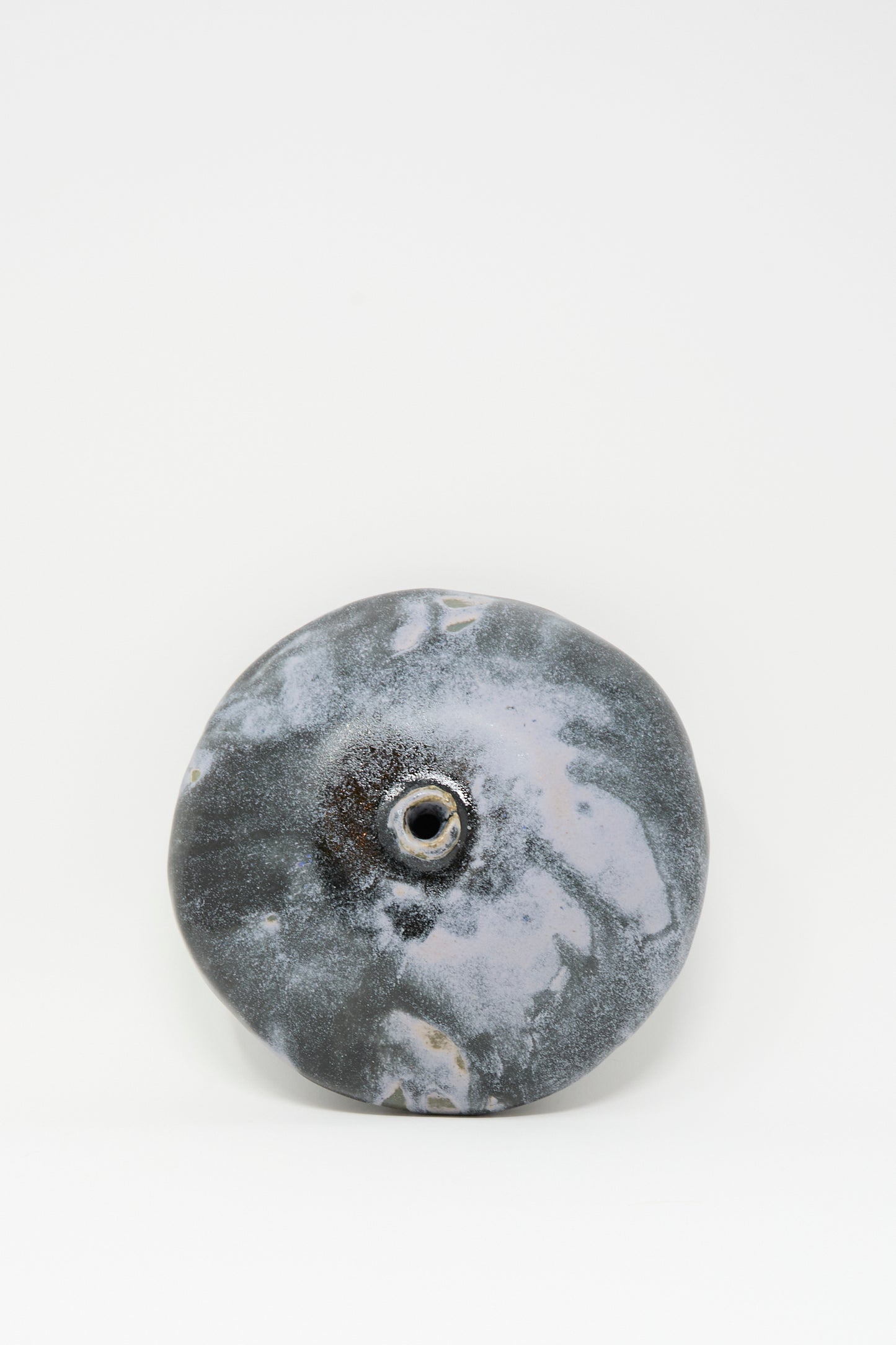 The Doyle Vase in Storm by MONDAYS is a round, gray handmade vase featuring a central hole and marbled surface, displayed on a plain white background.