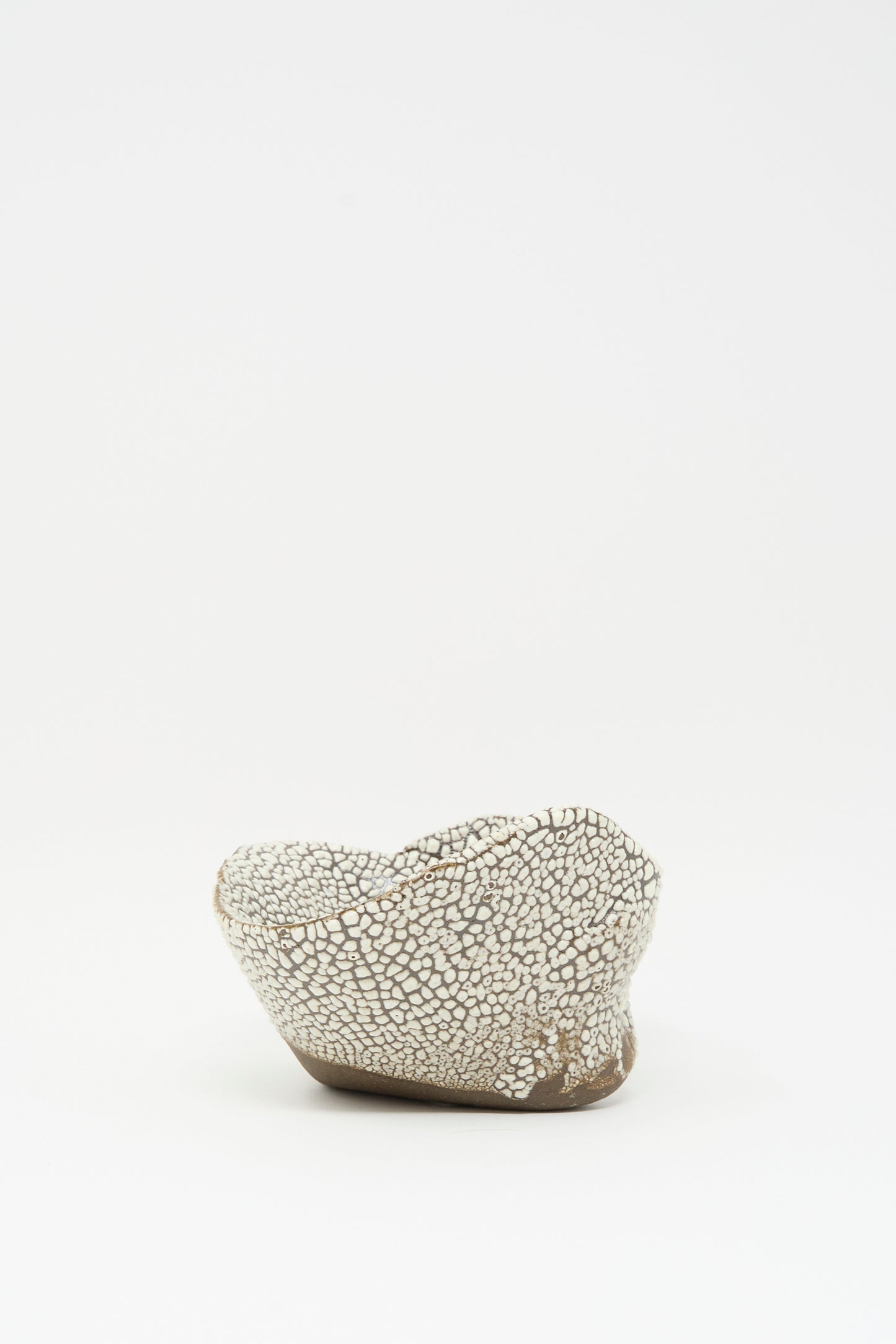 The Folded Bowl in Crawl I by MONDAYS features a textured, irregular form with a white crackled glaze, displayed on a plain white background—an example of modern Brooklyn ceramic artistry.