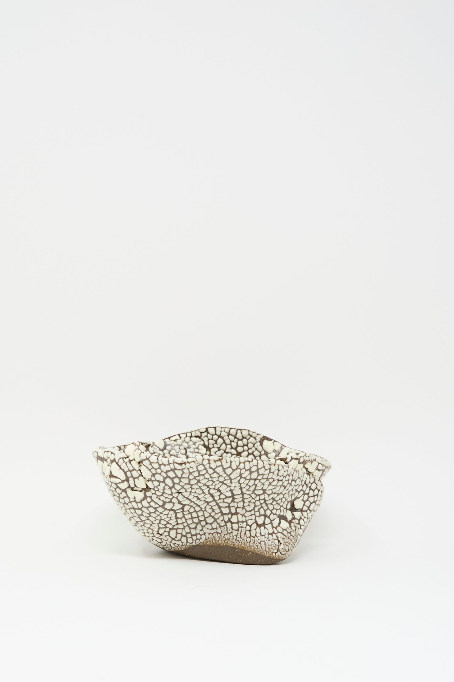The MONDAYS Folded Bowl in Crawl II features a hand-built, shallow form with a crackled white glaze and uneven rim, showcased on a plain white background.