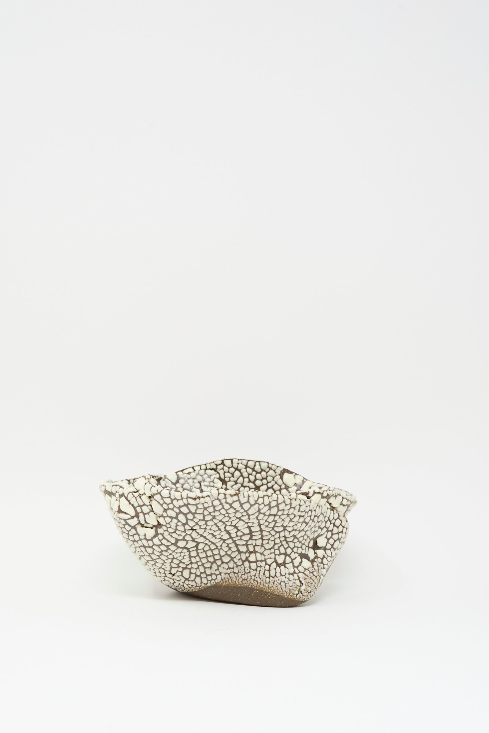 The MONDAYS Folded Bowl in Crawl II features a hand-built, shallow form with a crackled white glaze and uneven rim, showcased on a plain white background.