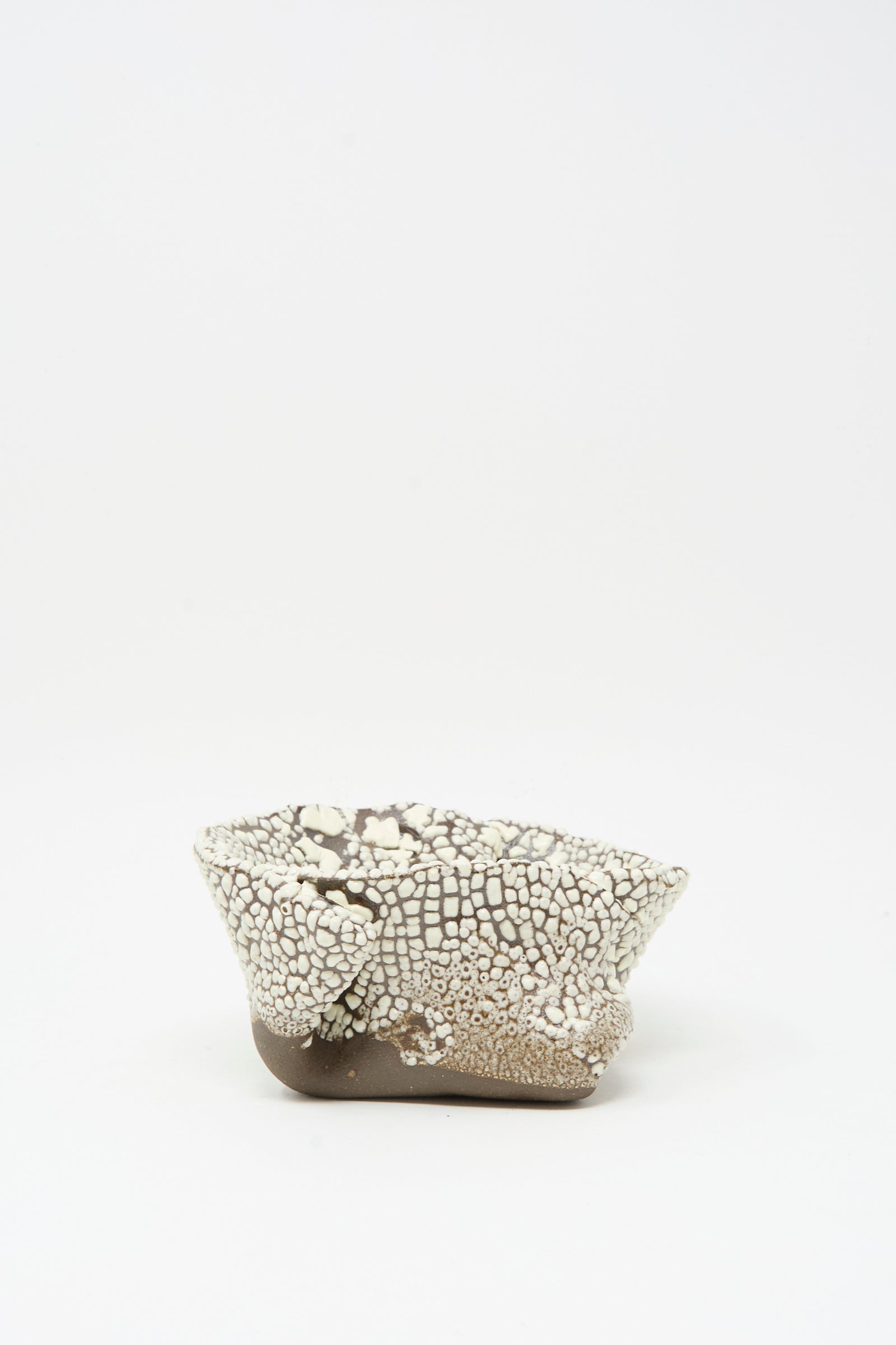 The MONDAYS Folded Wavy Bowl in Crawl II is a small, hand-built piece from Brooklyn featuring a textured crawling white glaze over a smooth brown base, shown on a plain white background.