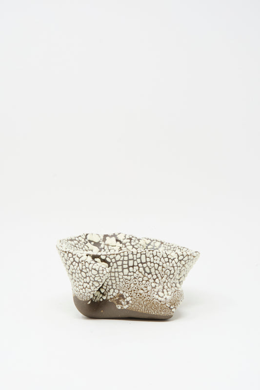 The MONDAYS Folded Wavy Bowl in Crawl II is a small, hand-built piece from Brooklyn featuring a textured crawling white glaze over a smooth brown base, shown on a plain white background.