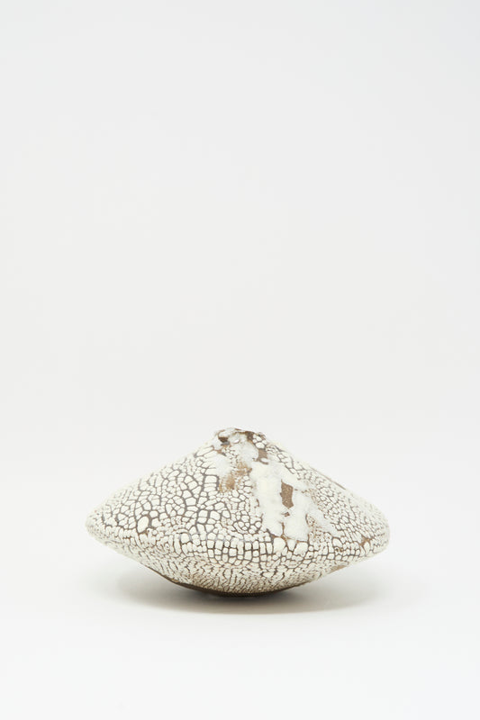 The Ikebana Vase in Crawl by MONDAYS, a round, flat white ceramic piece with a cracked crawling glaze, sits on a plain white background.