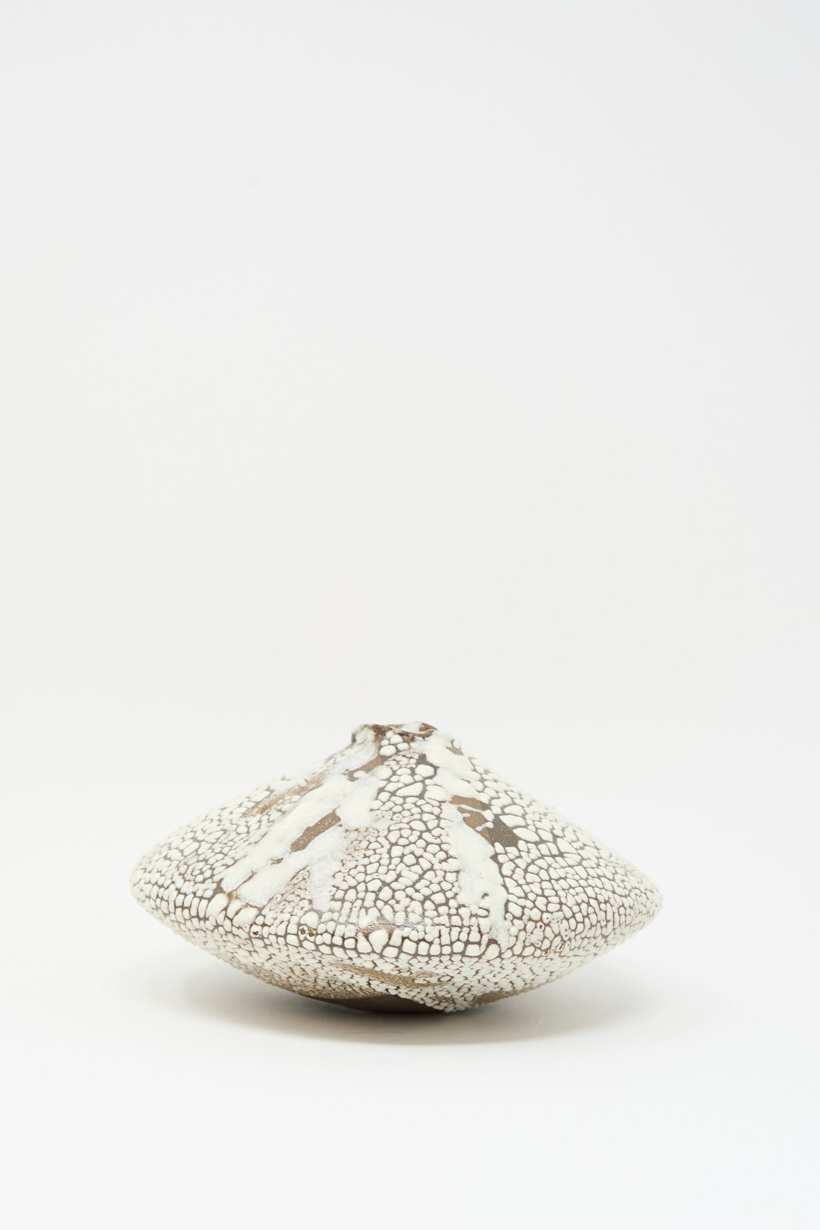 The Ikebana Vase in Crawl by MONDAYS features a wide, flat form with a narrow, uneven top and a crawling white glaze accented with brown. Shown against a plain white background.