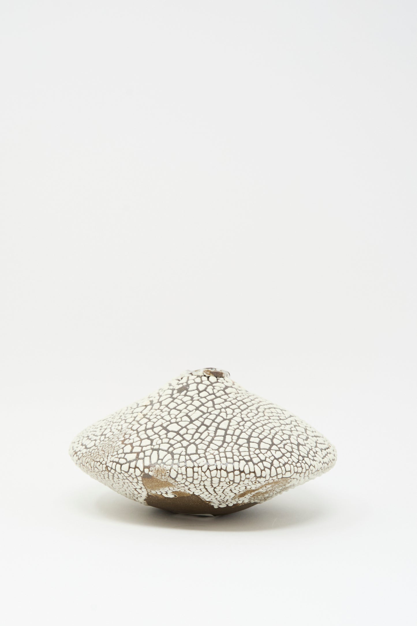 The Ikebana Vase in Crawl by MONDAYS is a hand-built, white, textured ceramic vase with a cracked finish and rounded, irregular shape shown on a plain white background.