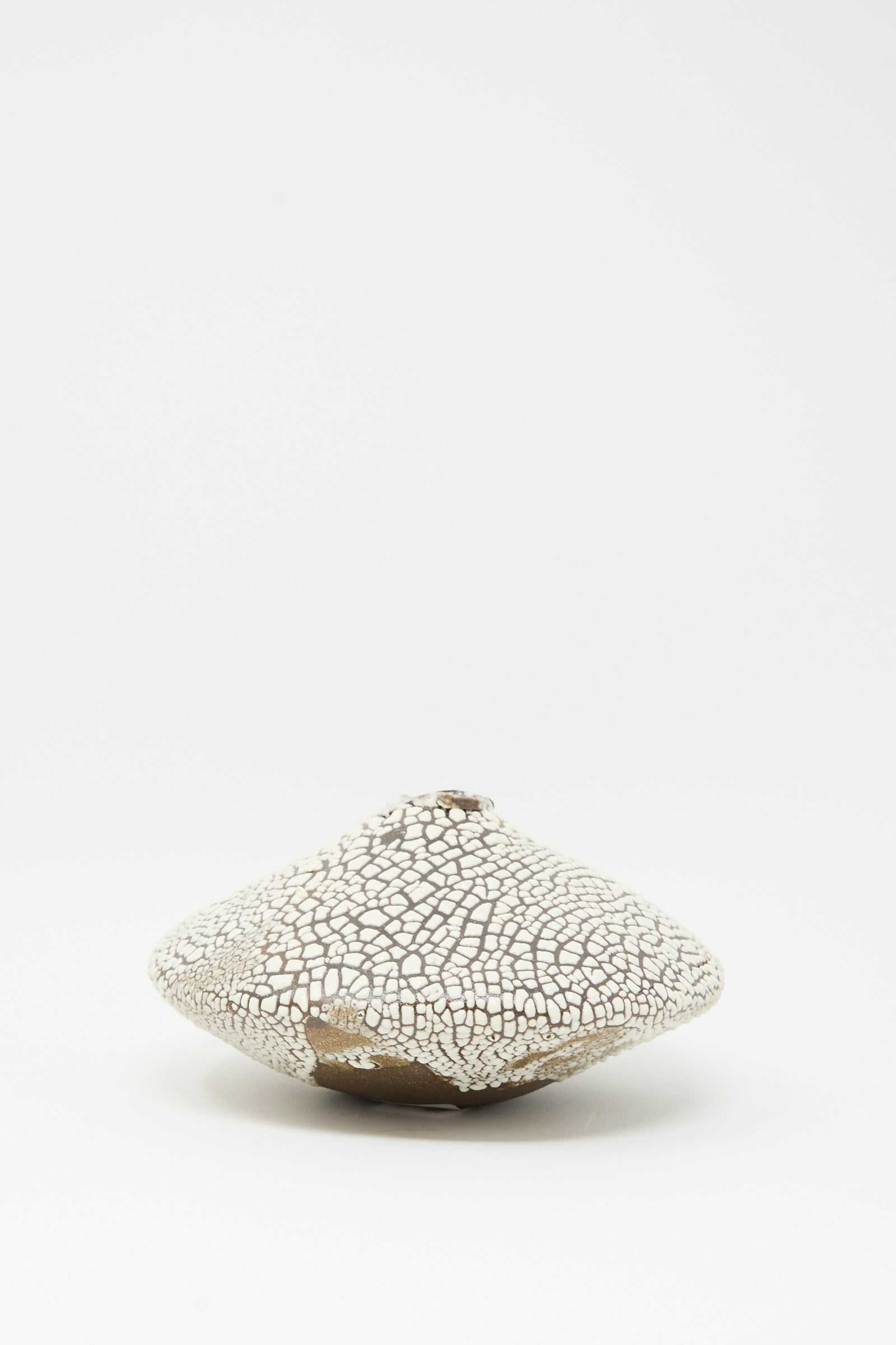The Ikebana Vase in Crawl by MONDAYS is a hand-built, white, textured ceramic vase with a cracked finish and rounded, irregular shape shown on a plain white background.