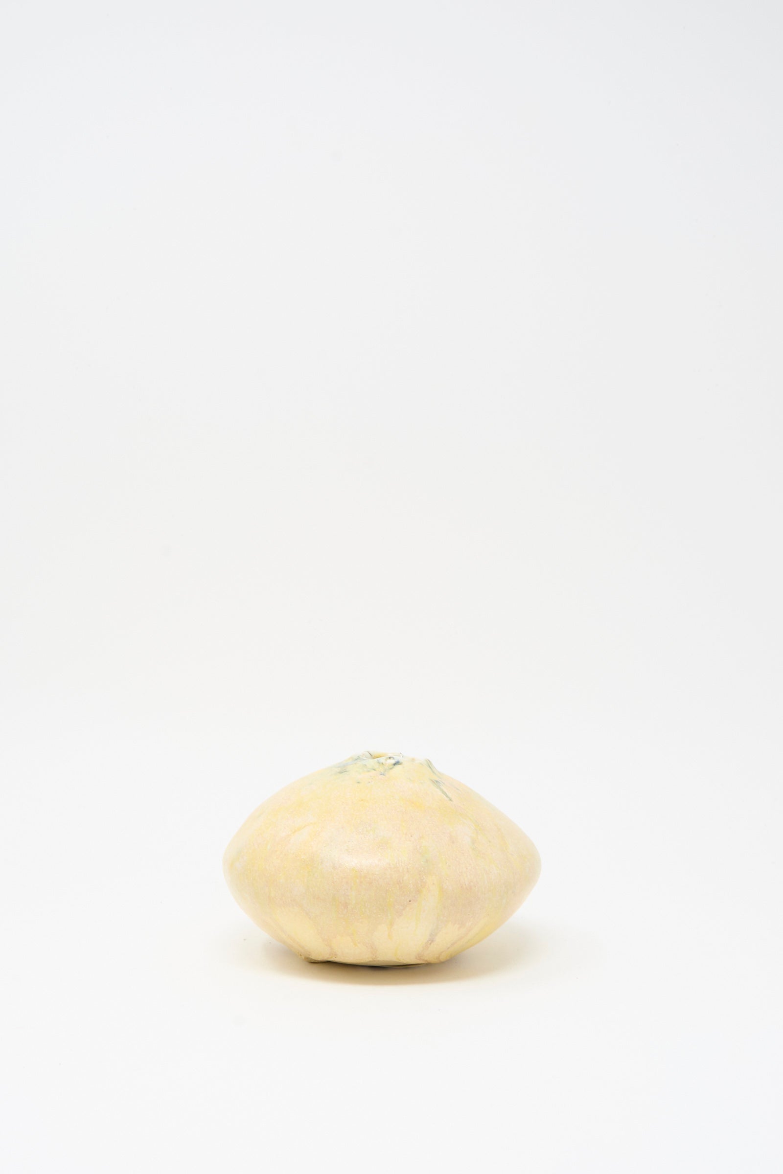 A handmade MONDAYS Mini Moon Vase in Yellow Multi sits beside a round, pale yellow fruit on a white background.