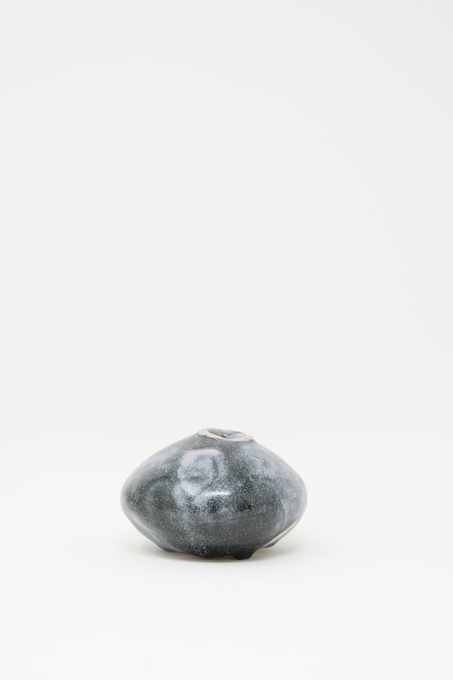The MONDAYS Moon Vase in Storm features a small, dark ceramic body with a rounded, irregular shape and subtle blue glaze, displayed against a plain white background.