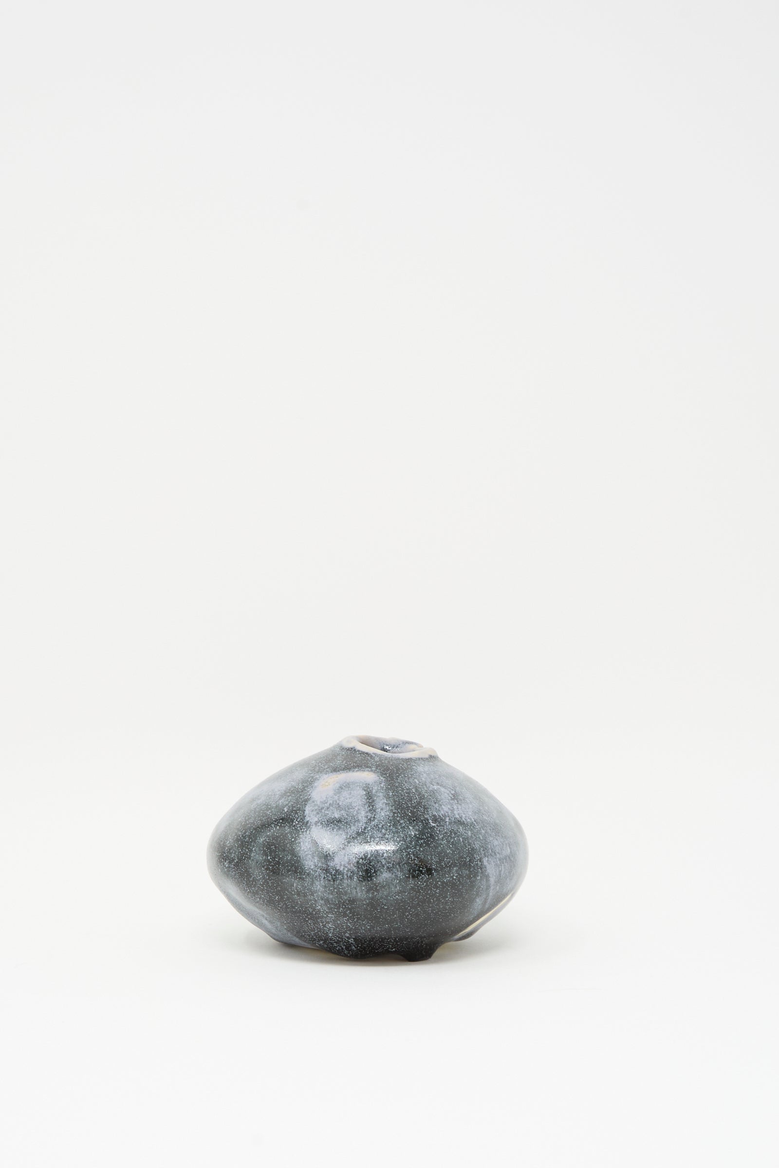 The MONDAYS Moon Vase in Storm features a small, dark ceramic body with a rounded, irregular shape and subtle blue glaze, displayed against a plain white background.