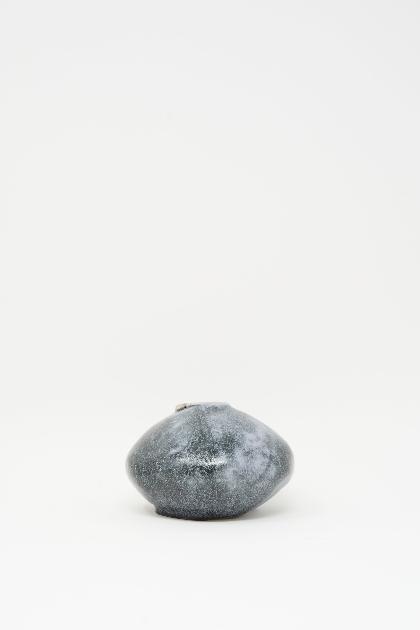 The MONDAYS Moon Vase in Storm is a small, round, dark gray ceramic vase with a narrow opening and subtle blue glaze accents, displayed centered on a plain white background.