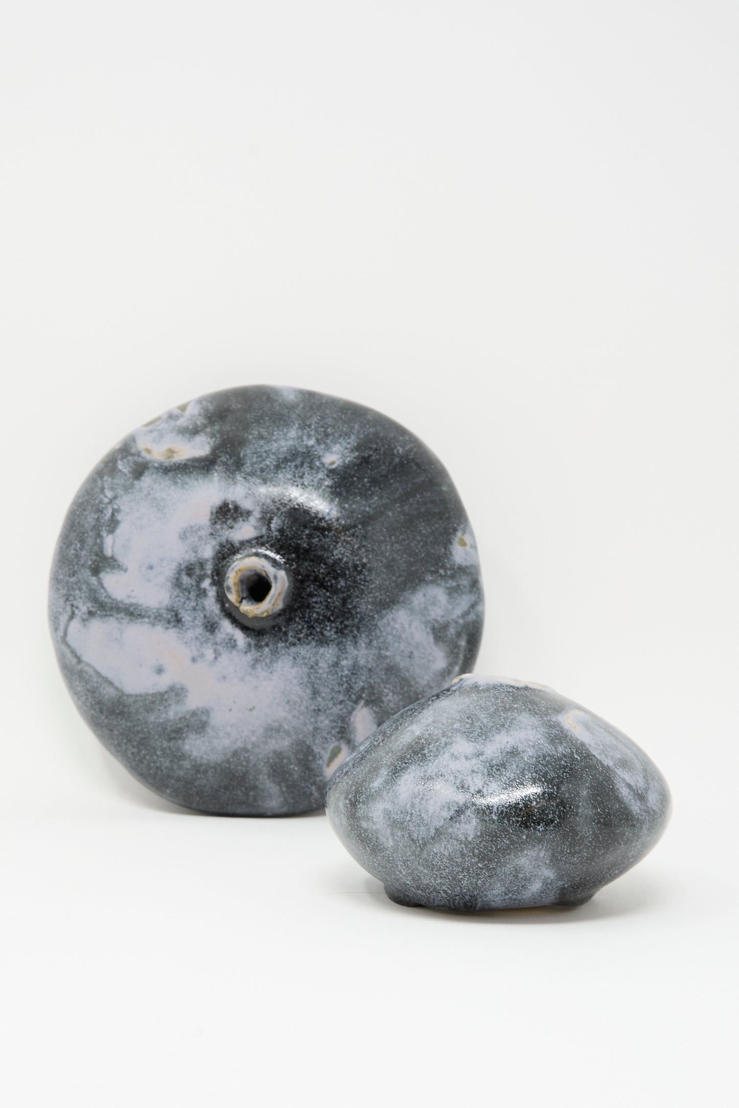 Two round, handmade Doyle Vases in Storm by MONDAYS, featuring a gray-blue and white glazed finish, are displayed against a plain white background.