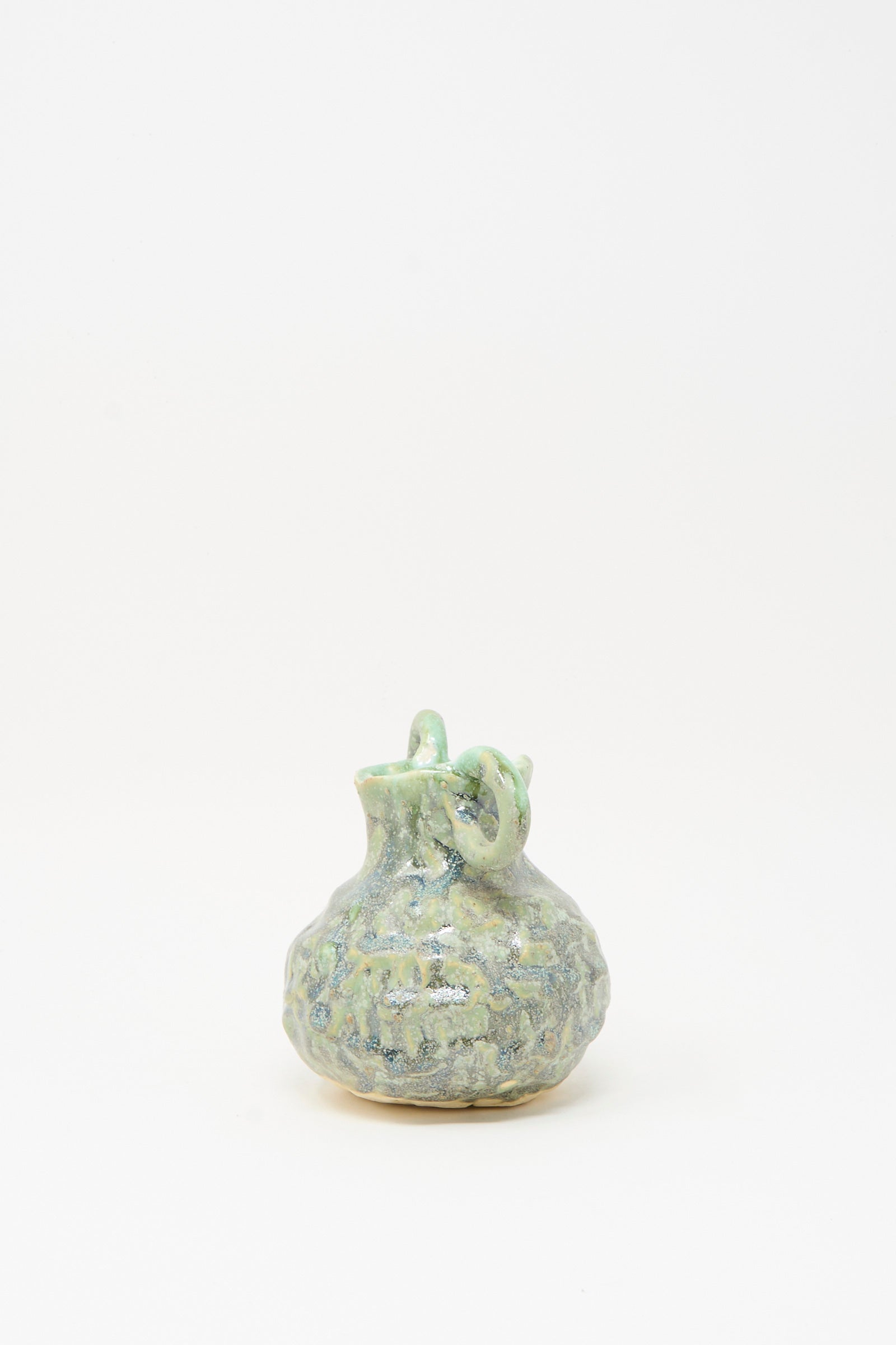 The MONDAYS Pinched Vase with Handles in Green is a small, round, handmade vase featuring two handles and a narrow neck, displayed against a plain white background.