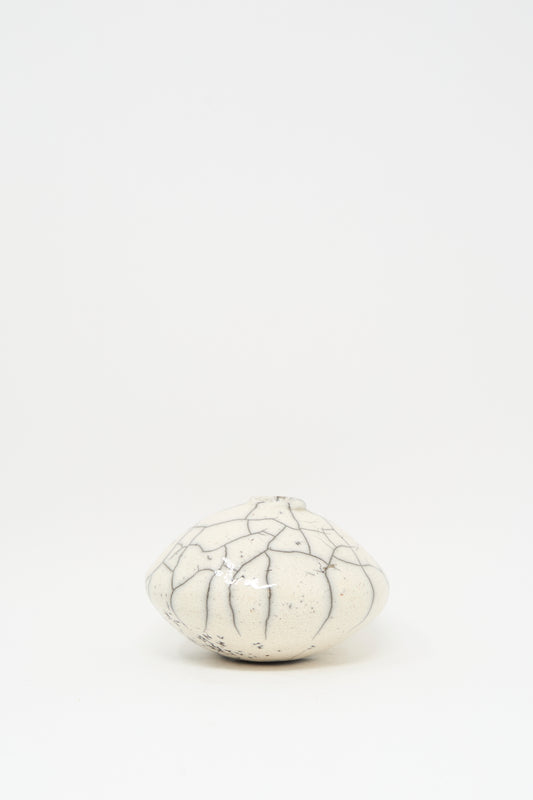 The MONDAYS Raku Moon Vase in White is a small, round ceramic piece with dark, irregular crackle lines, set against a plain white background.