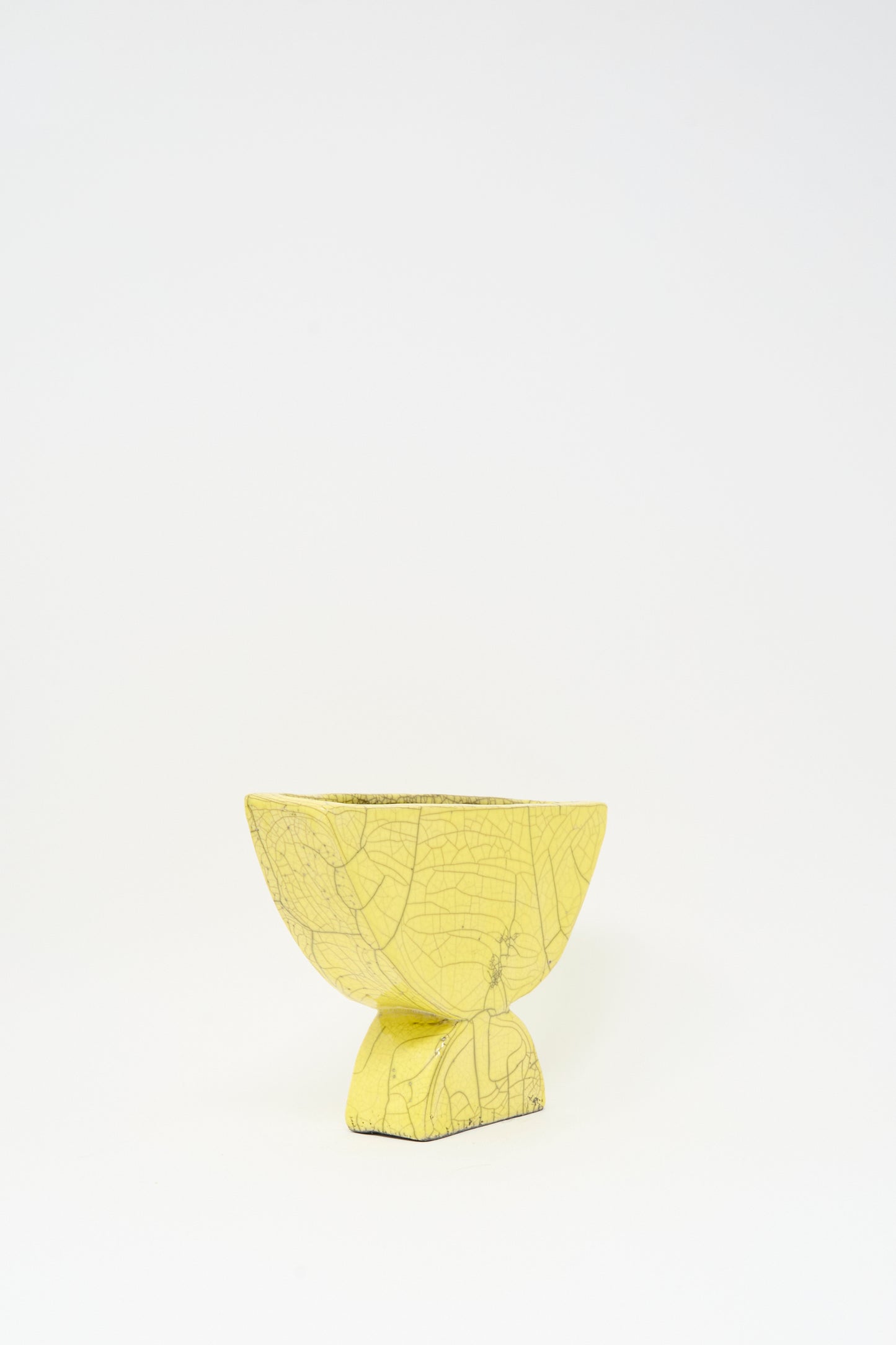 The MONDAYS Raku Semicircle Vessel in Yellow is a small ceramic bowl featuring a textured, crackled finish and a square base, inspired by Raku-fired art, shown against a plain white background.