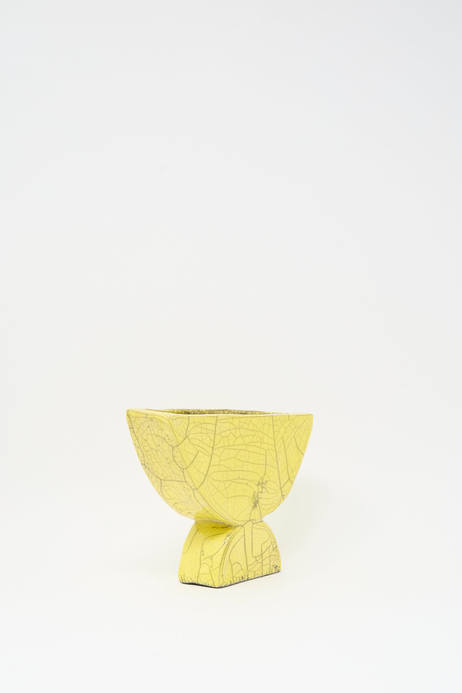 The MONDAYS Raku Semicircle Vessel in Yellow is a small ceramic bowl featuring a textured, crackled finish and a square base, inspired by Raku-fired art, shown against a plain white background.