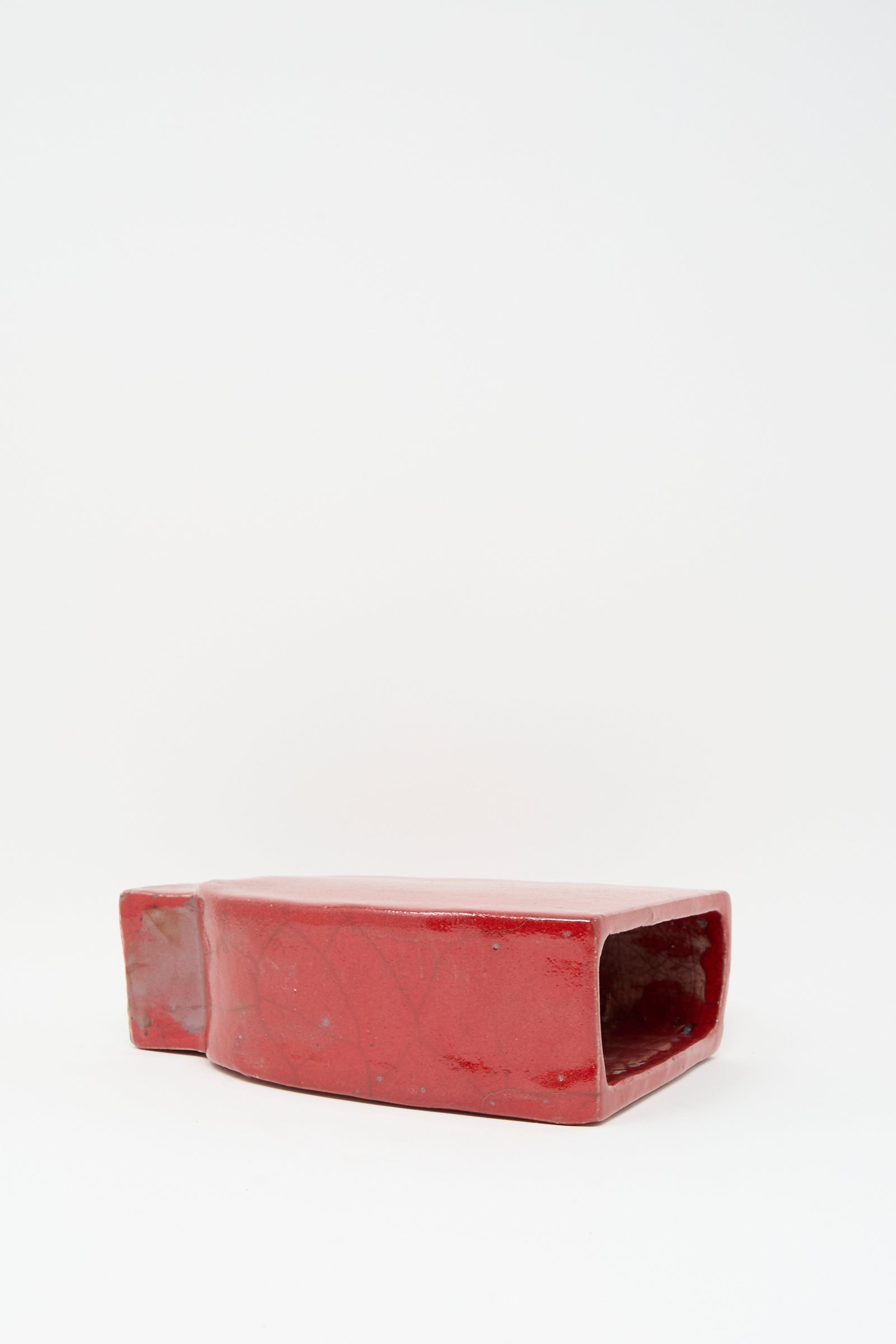 The MONDAYS Raku Vessel in Red is a rectangular, glossy handmade vase with a wide open mouth, shown on its side against a plain white background.