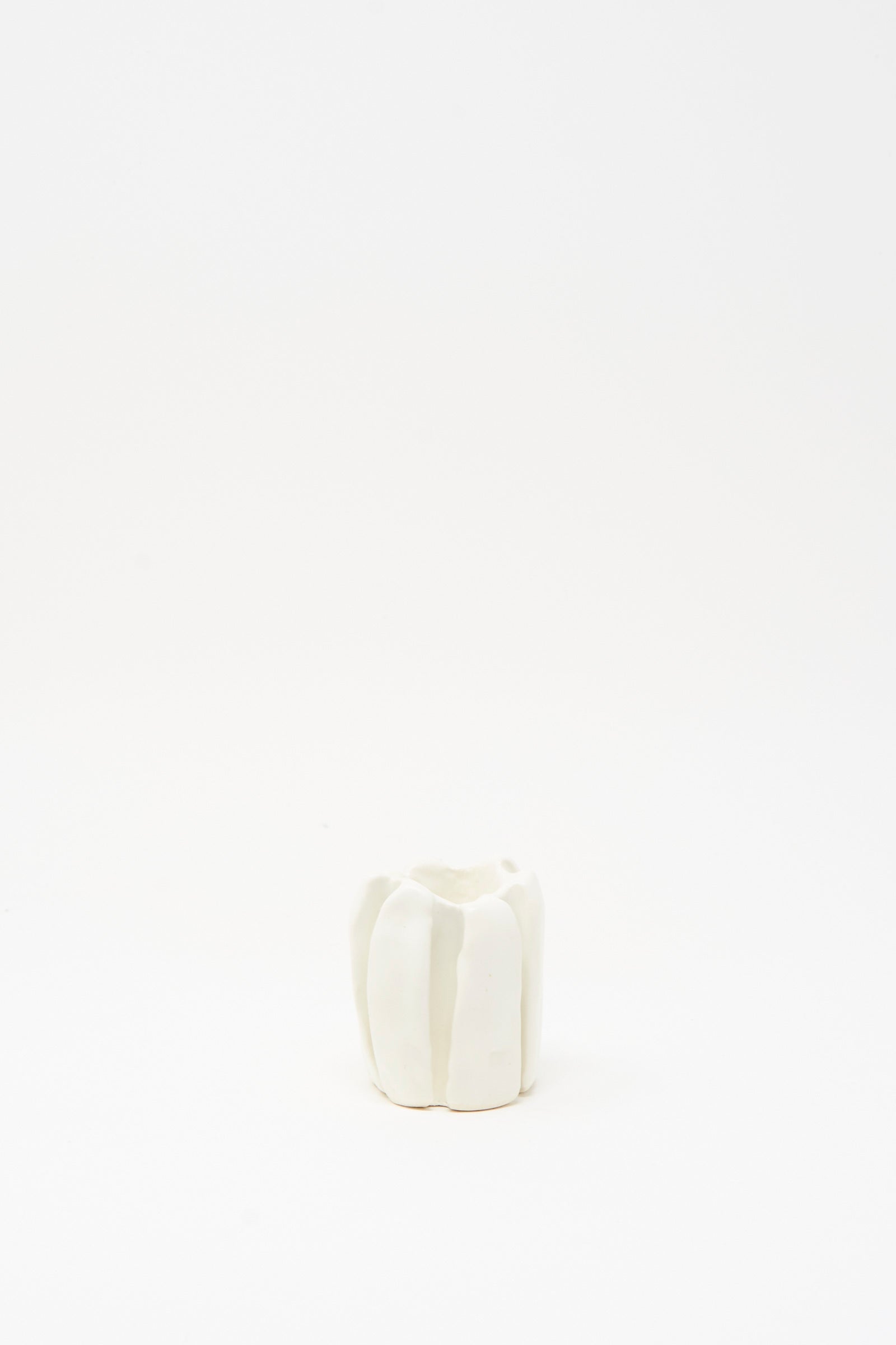 The MONDAYS Ribbed Candleholder in White, featuring vertical grooves and crafted from porcelain, is centered on a plain white background.