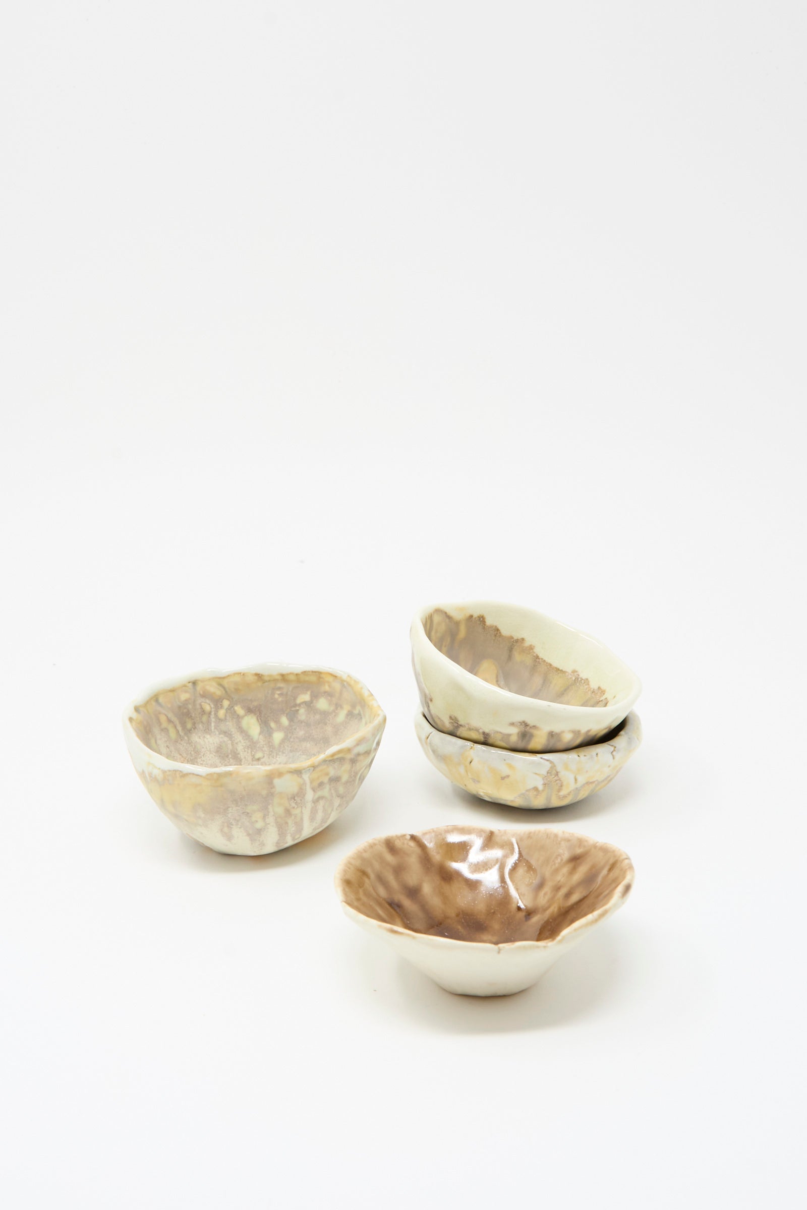 Four MONDAYS Small Pinched Bowls in Brown, each with unique beige and brown glazes and hand-pinched edges, are arranged on a plain white background.