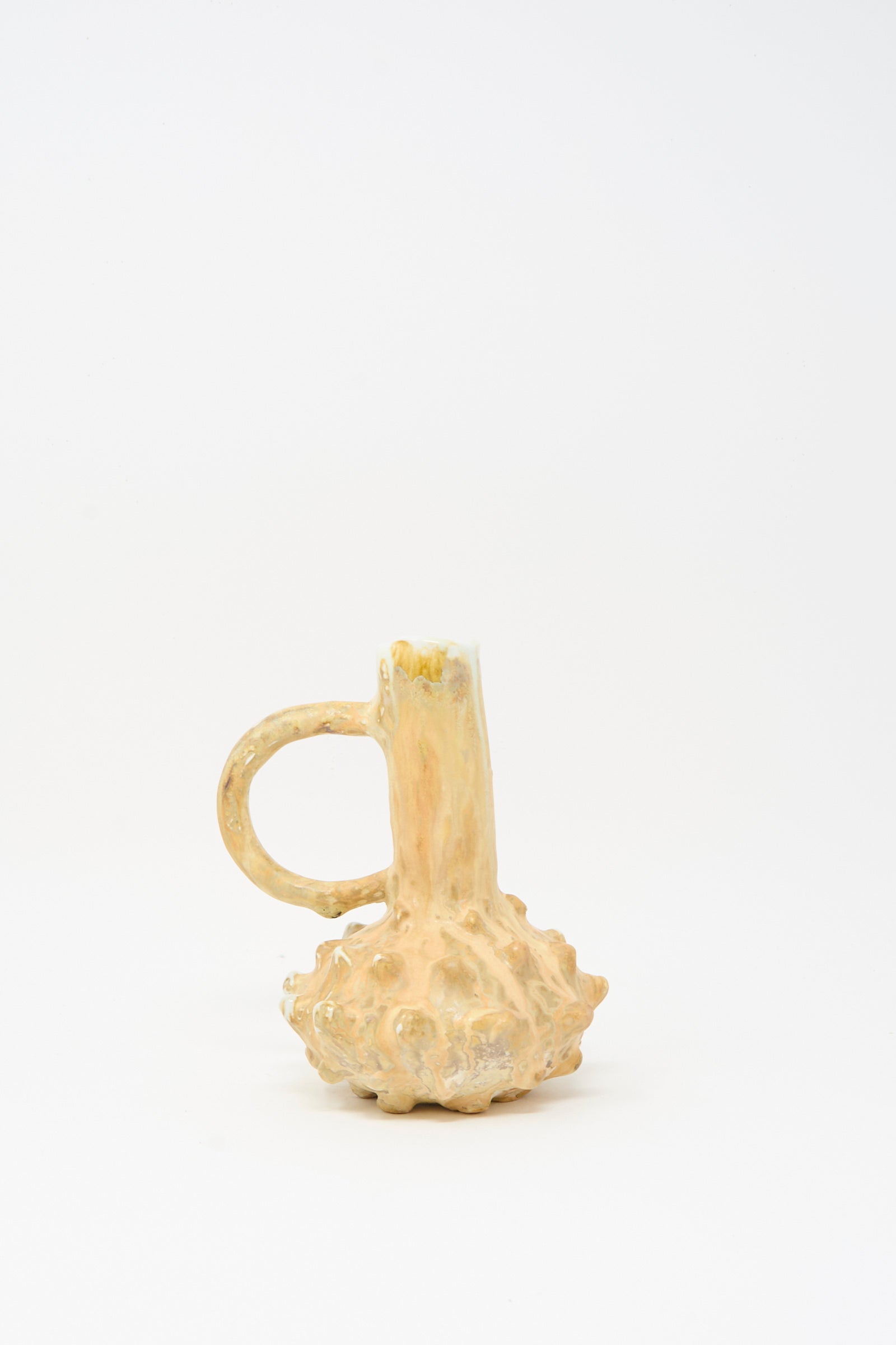 The MONDAYS Soda-Fired Bottle Vase No. 7 features a handmade, textured surface with a single handle and is glazed in light beige and orange tones, displayed on a plain white background.