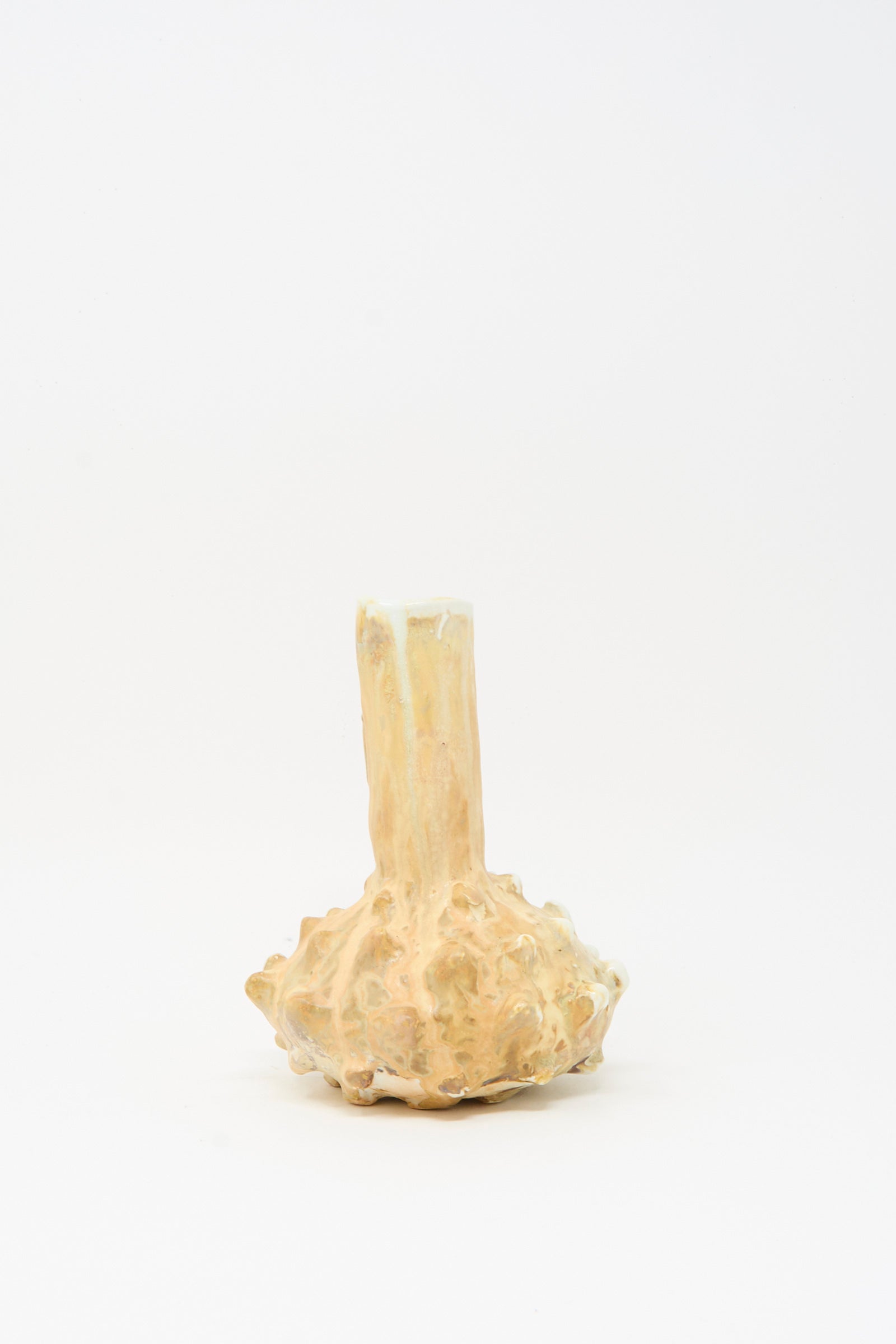 The MONDAYS Soda-Fired Bottle Vase No. 7 is a small, beige handmade vase featuring a rough, textured bulbous base and a narrow, uneven neck, showcased against a plain white background.