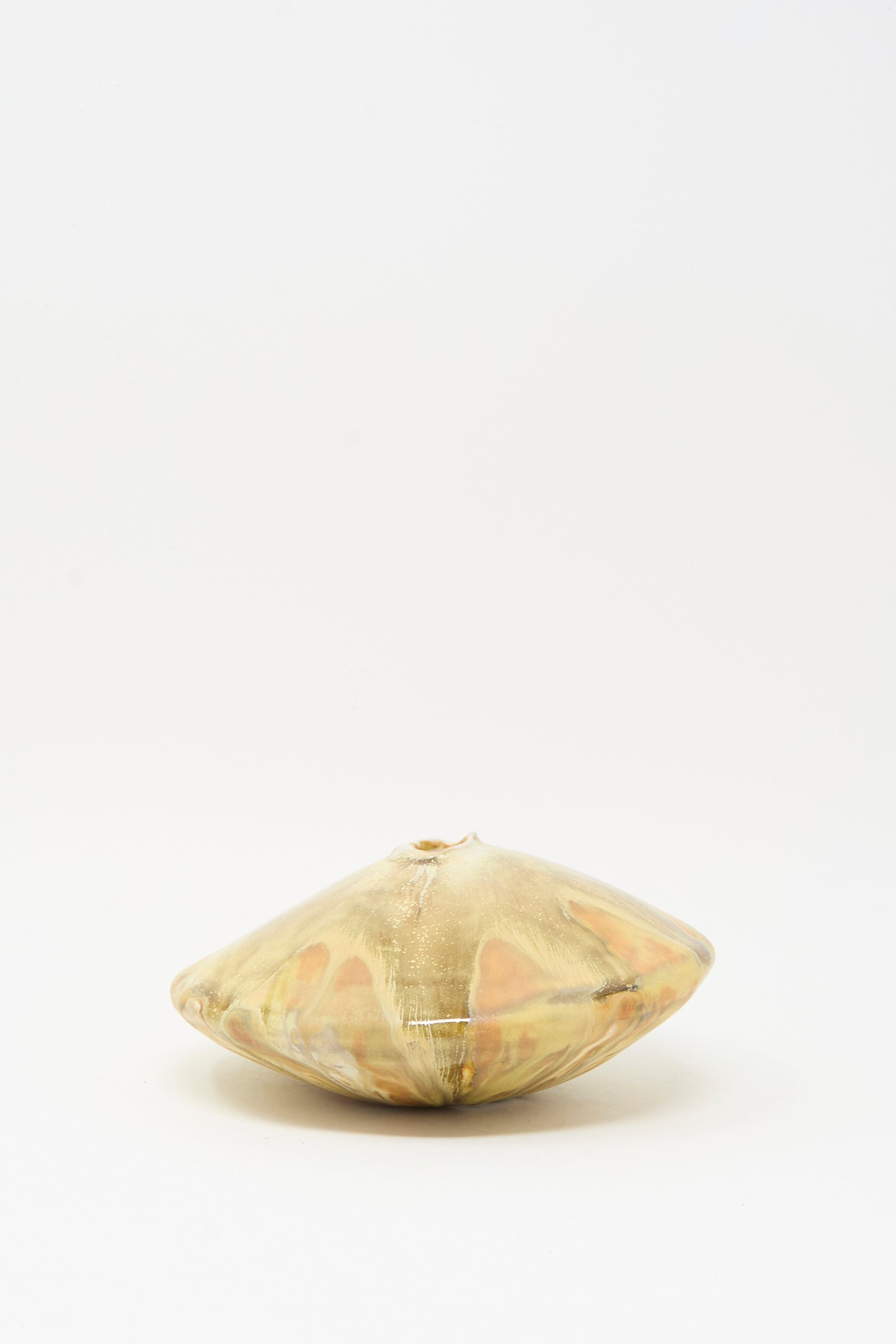 The MONDAYS Soda-Fired Ikebana Vase No. 1 is a small, round handmade ceramic vase with a flattened shape, narrow top opening, and yellowish-brown marbled glaze on soda-fired porcelain, shown against a plain white background.