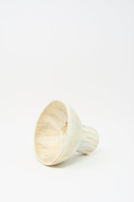 The MONDAYS Soda-Fired Pedestal Bowl, a light-colored, cone-shaped handmade ceramic piece with a hollow center, is displayed on its side against a plain white background.