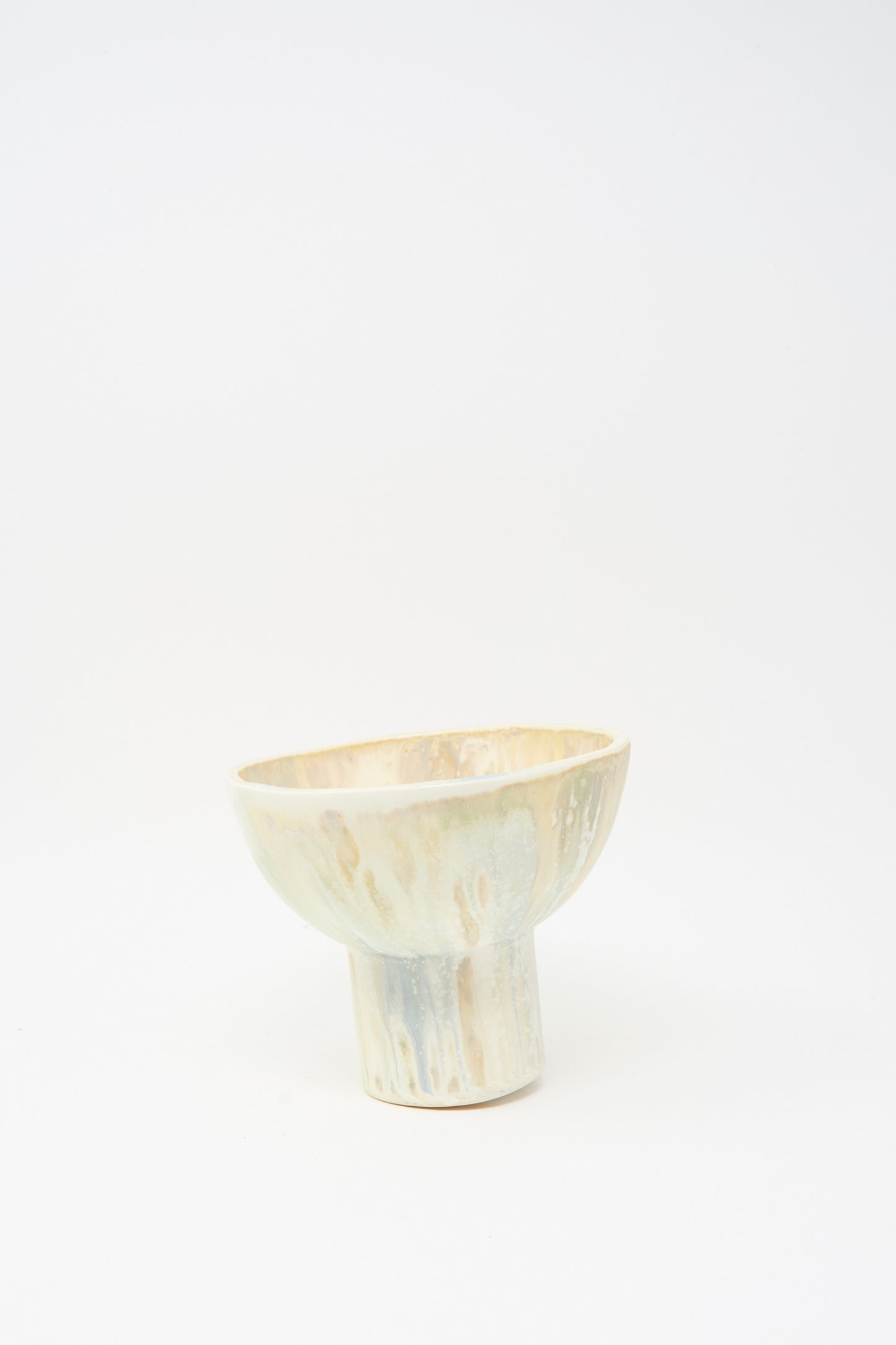 The MONDAYS Soda-Fired Pedestal Bowl is a handmade porcelain piece with a textured, light beige and gray glaze, displayed on a white background.